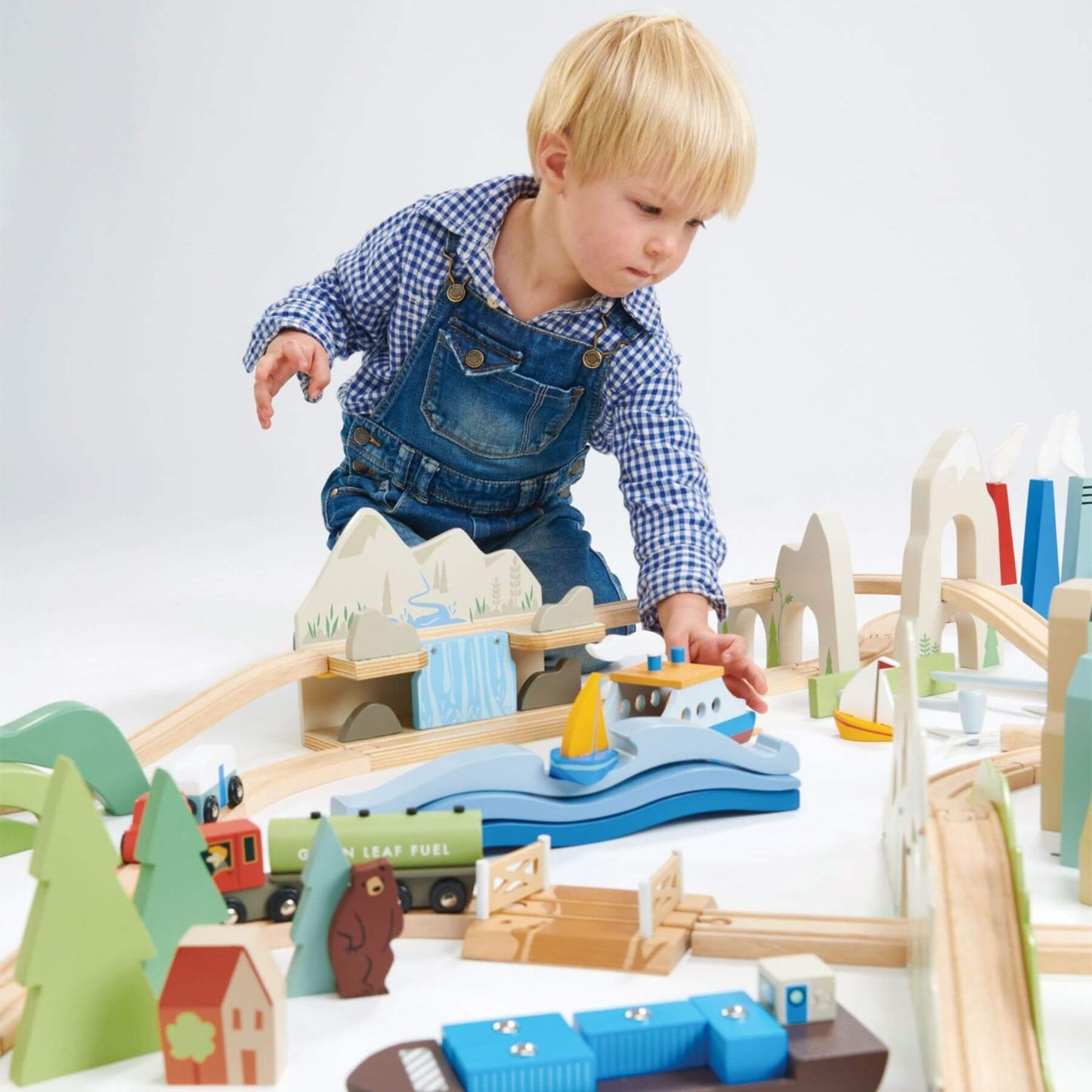 Child playing with Tender Leaf Mountain View Train Set on a white background