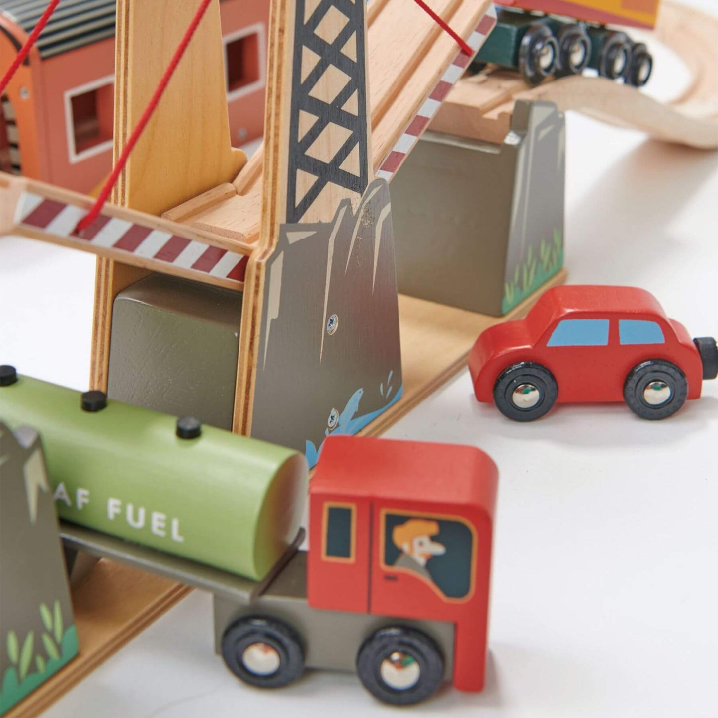Wooden toy set with a fuel truck, car, and building structure on a white background