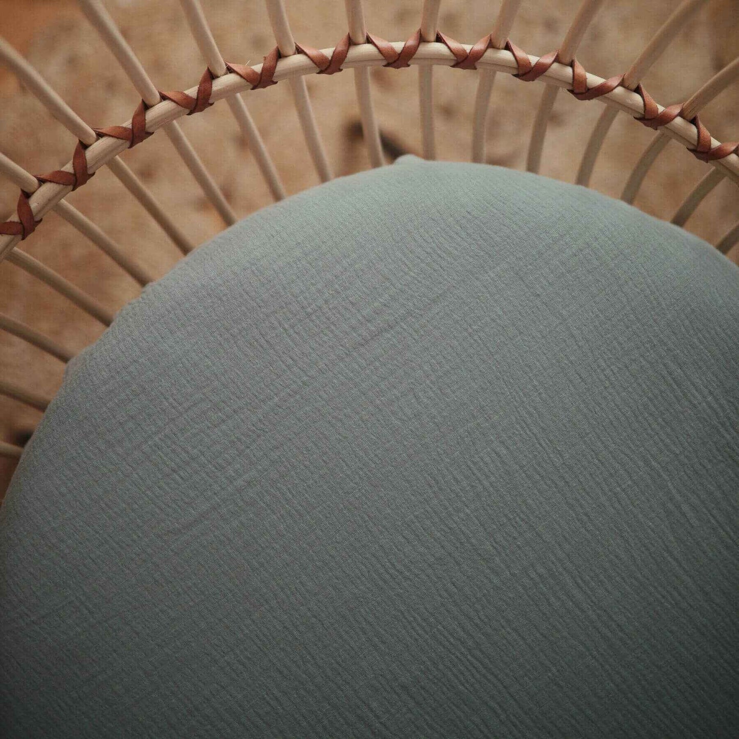 Close-up of a textured green cushion on a wicker chair