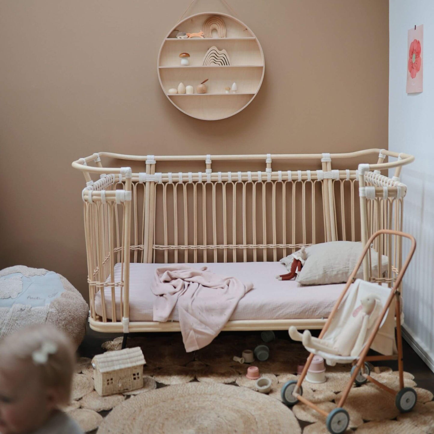 Nursery room with a crib, toys, and a baby in the corner.