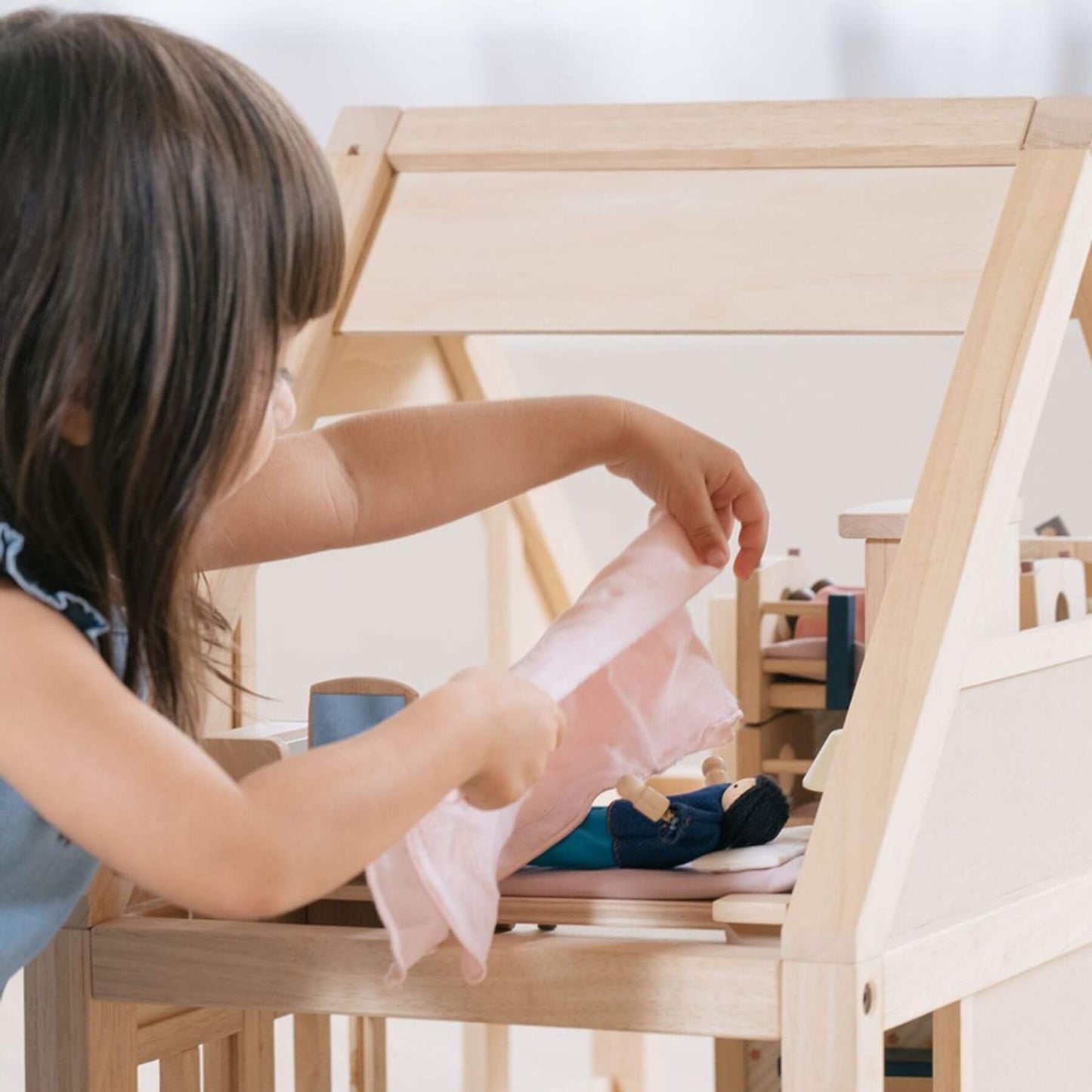 Child playing with PlanToys My First Dollhouse in a bright room.