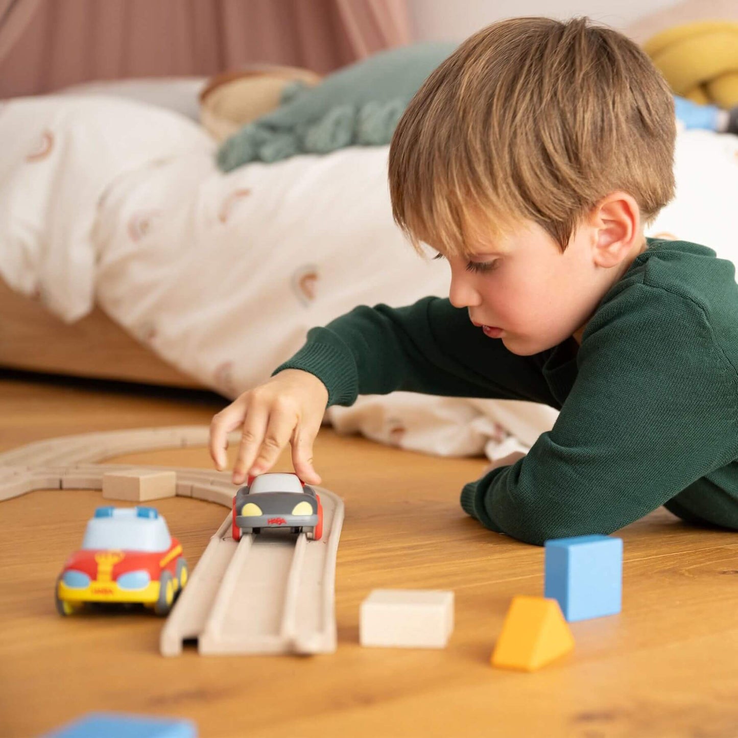 Child playing with HABA USA Cars - My First Racetrack on a wooden floor
