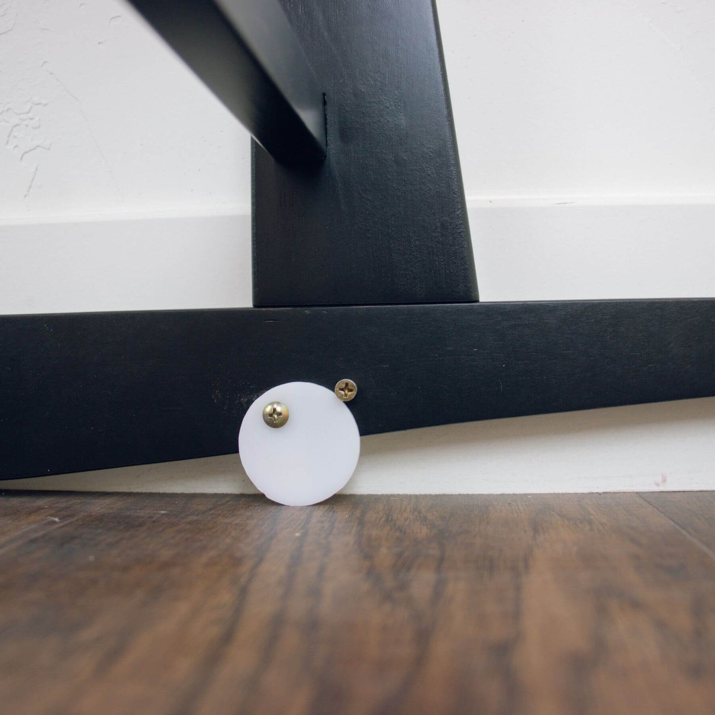 Close-up of Plum+Sparrow Original Rocking Moses Bassinet Stand with brake Black on a wooden floor.