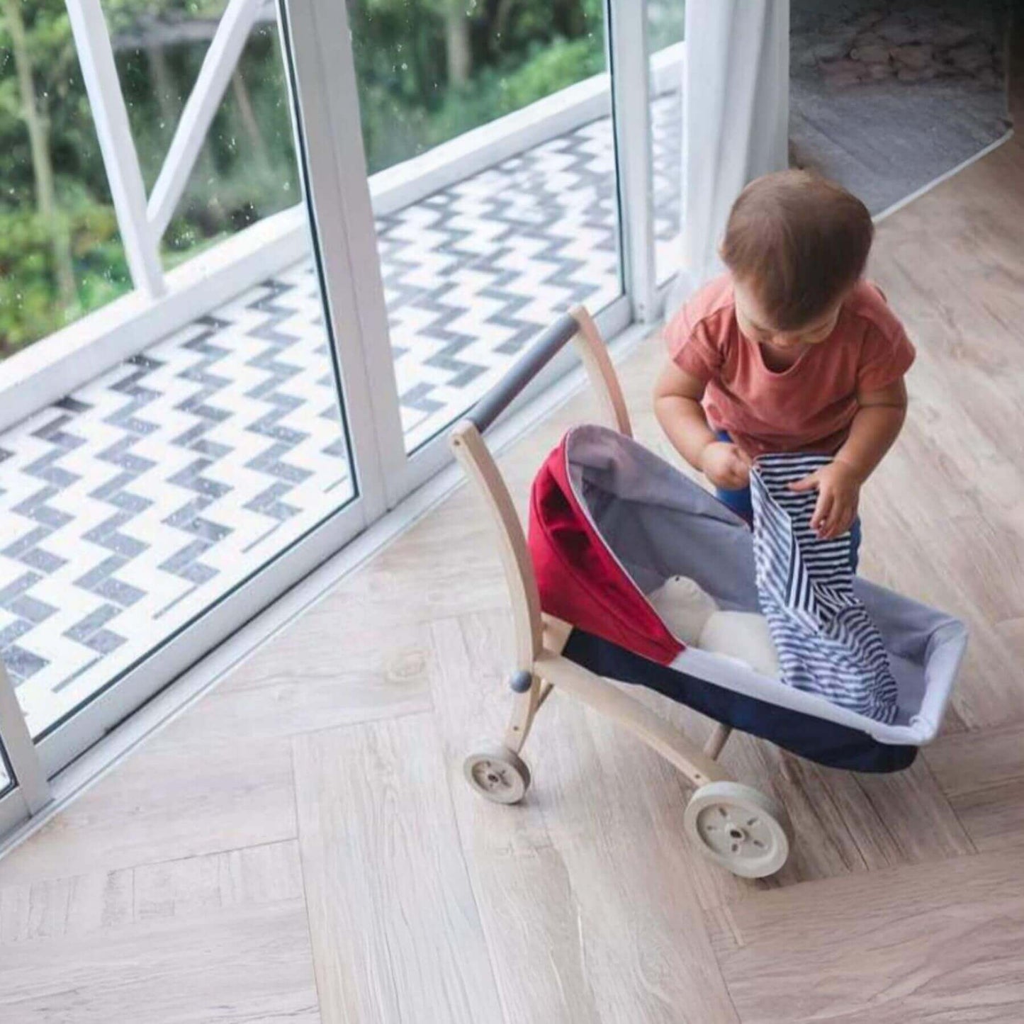 Child playing with PlanToys Doll Stroller indoors