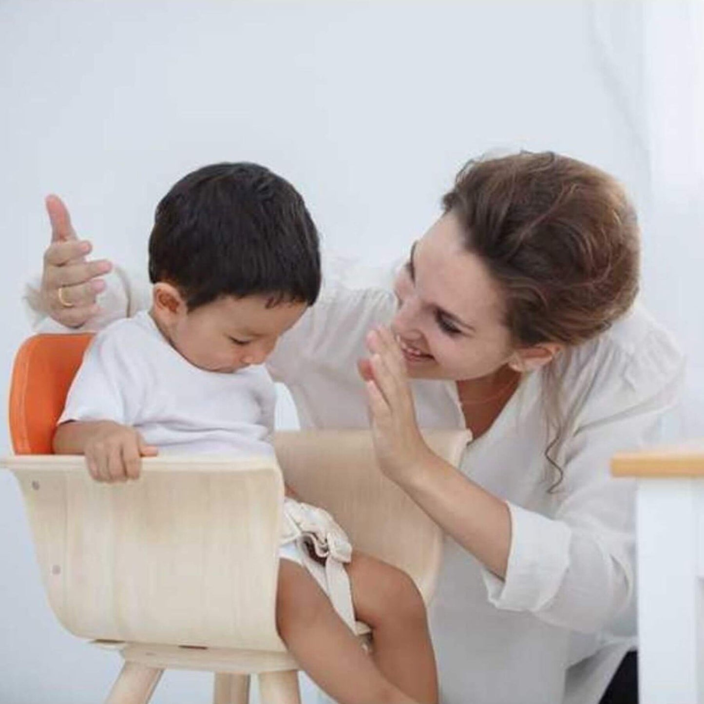 Woman and child sitting on PlanToys High Chair - Orange, engaging in a playful activity.