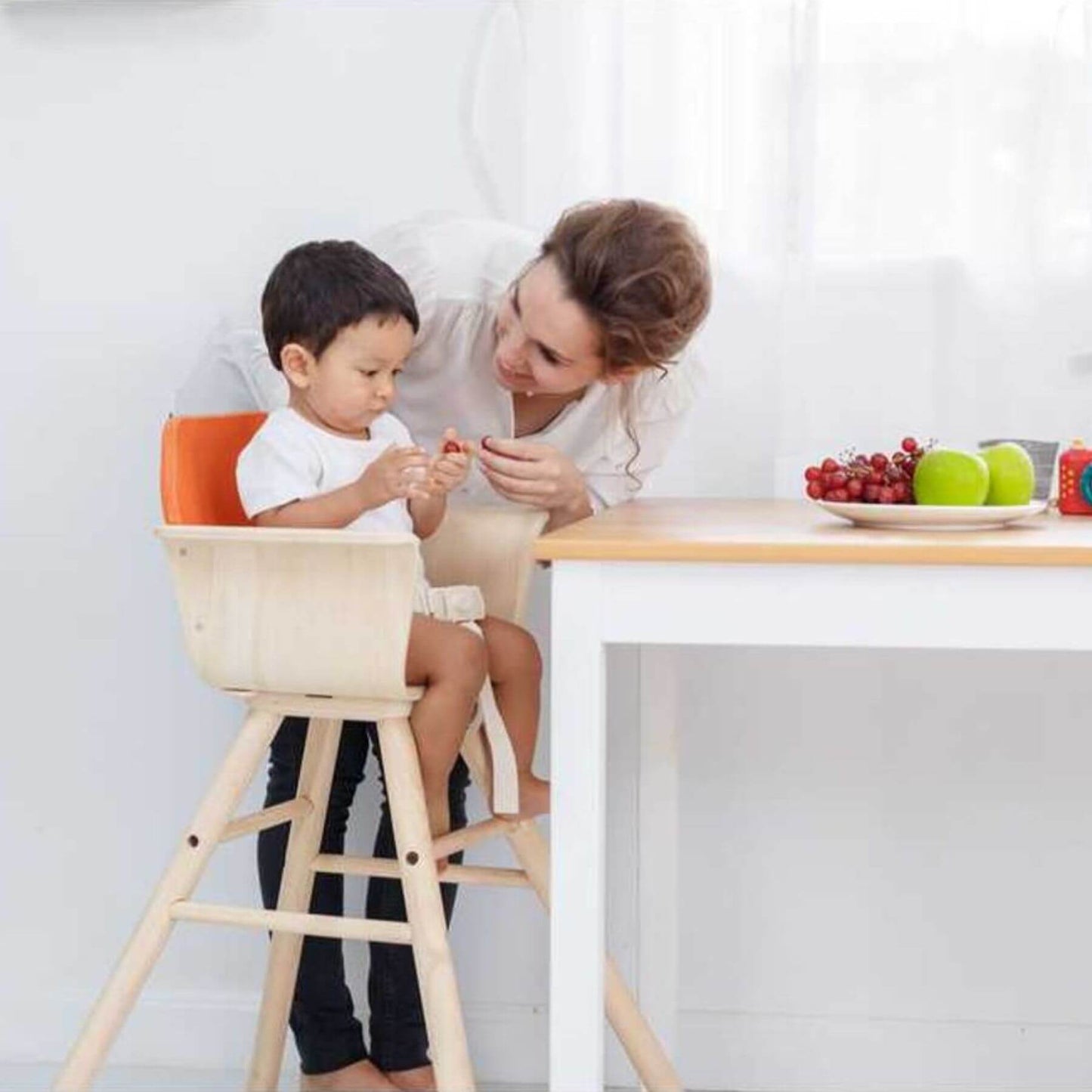 Woman and child sitting on PlanToys High Chair - Orange at a table with a plate of fruits