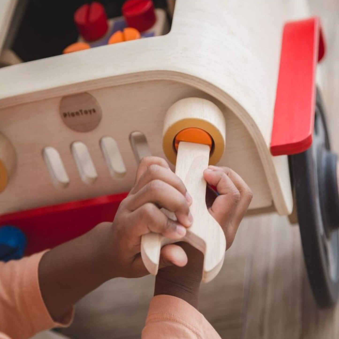 Child's hands playing with PlanToys Motor Mechanic