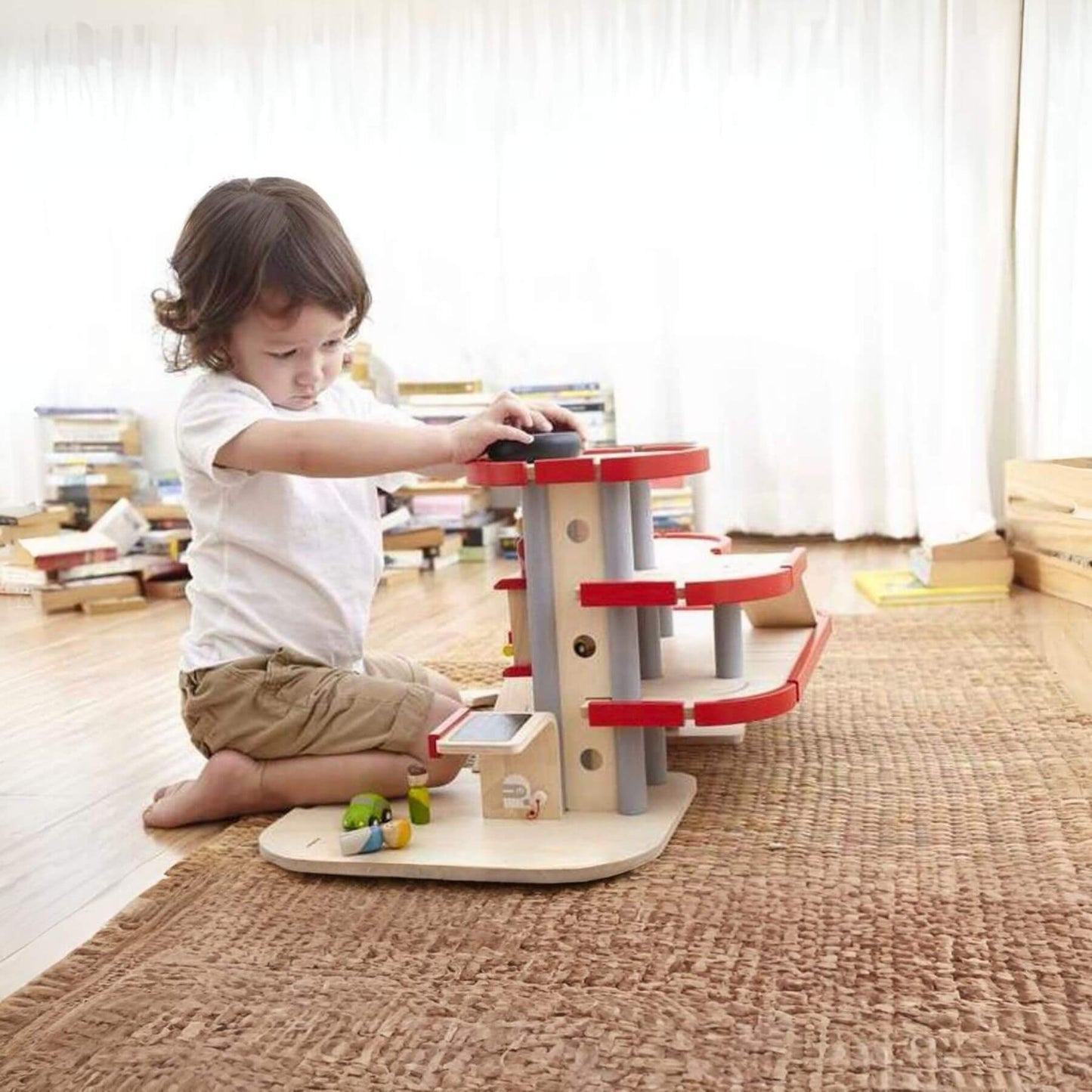 Child playing with PlanToys Parking Garage on a carpeted floor