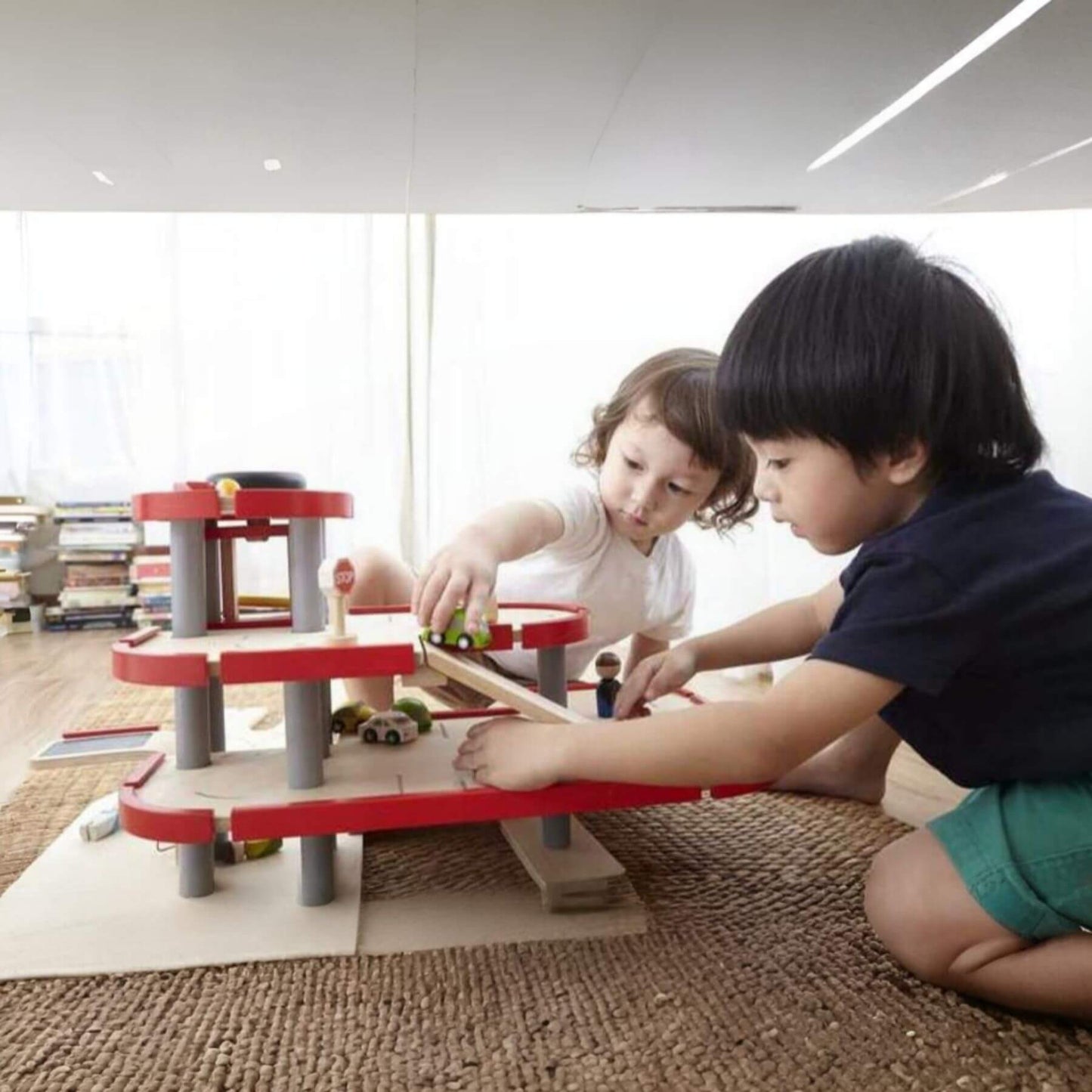 Two children playing with PlanToys Parking Garage indoors.