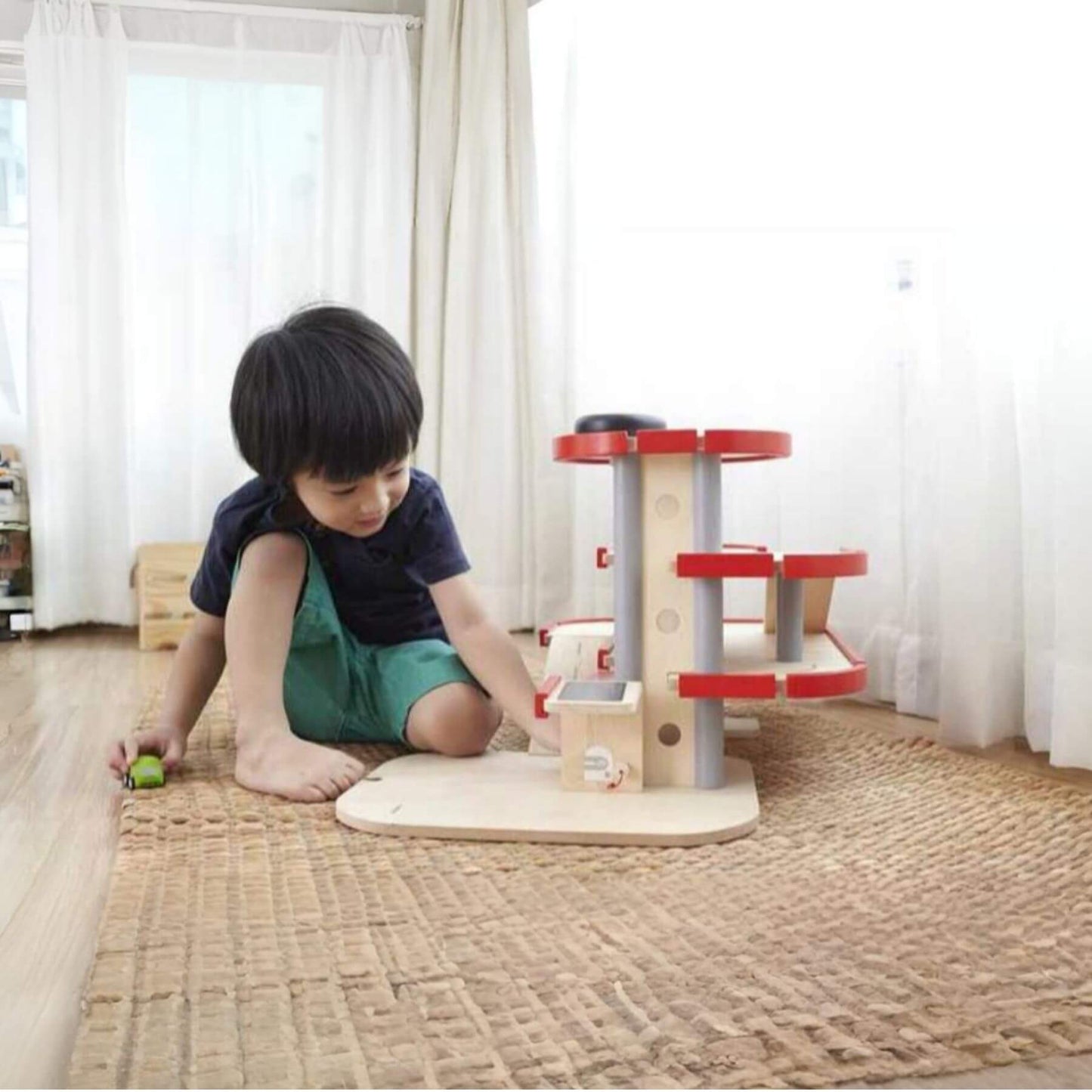 Child playing with PlanToys Parking Garage on a carpeted floor