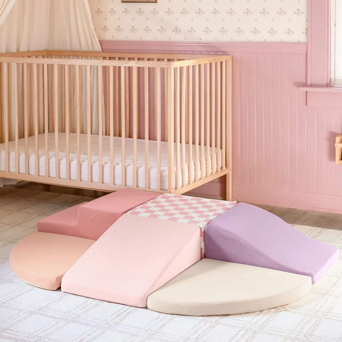 Tiny Land® PlayNest Climbing Blocks - Violet in a pink nursery, with a wooden crib in the background.