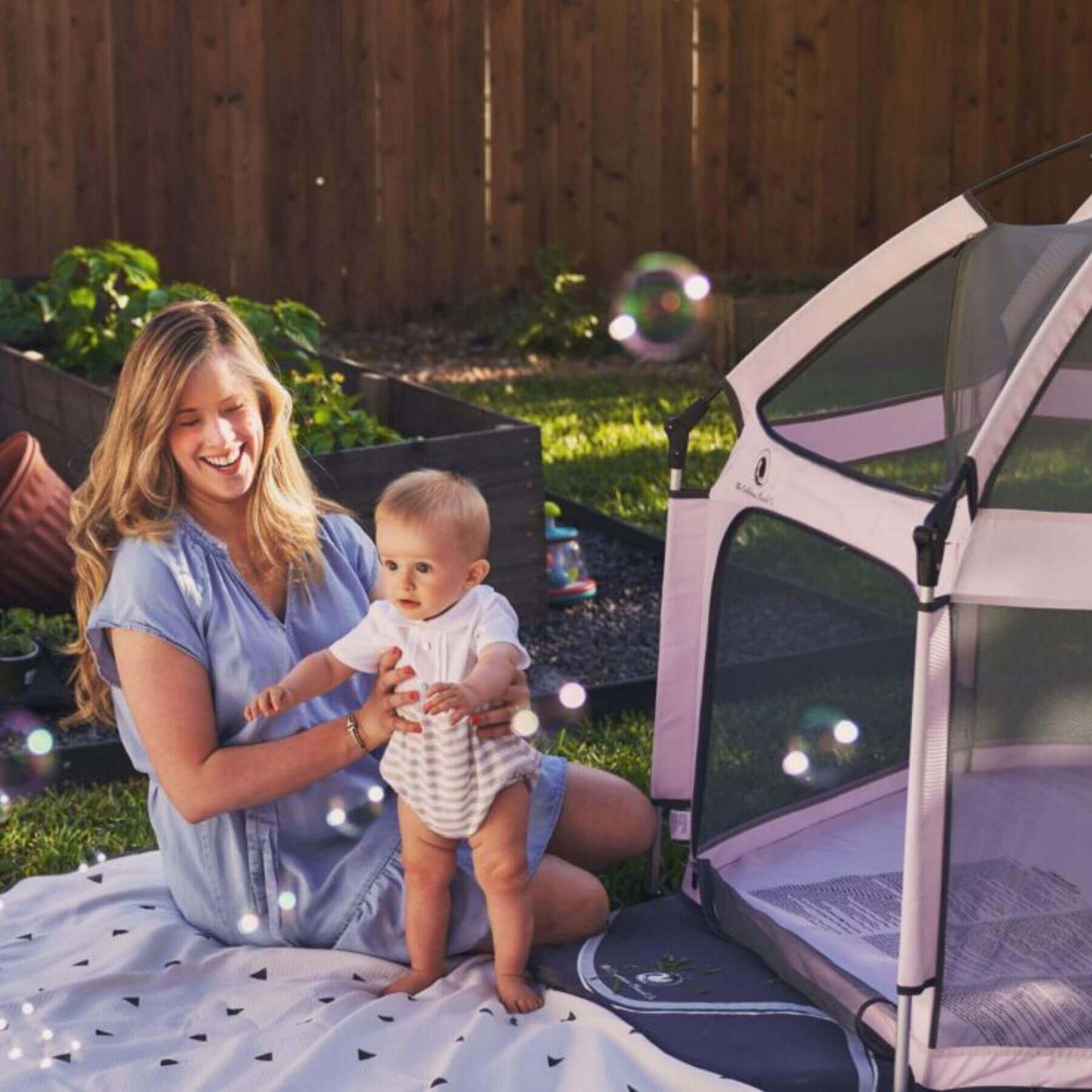 Mom holding baby outside Pop 'N Go™ Playpen