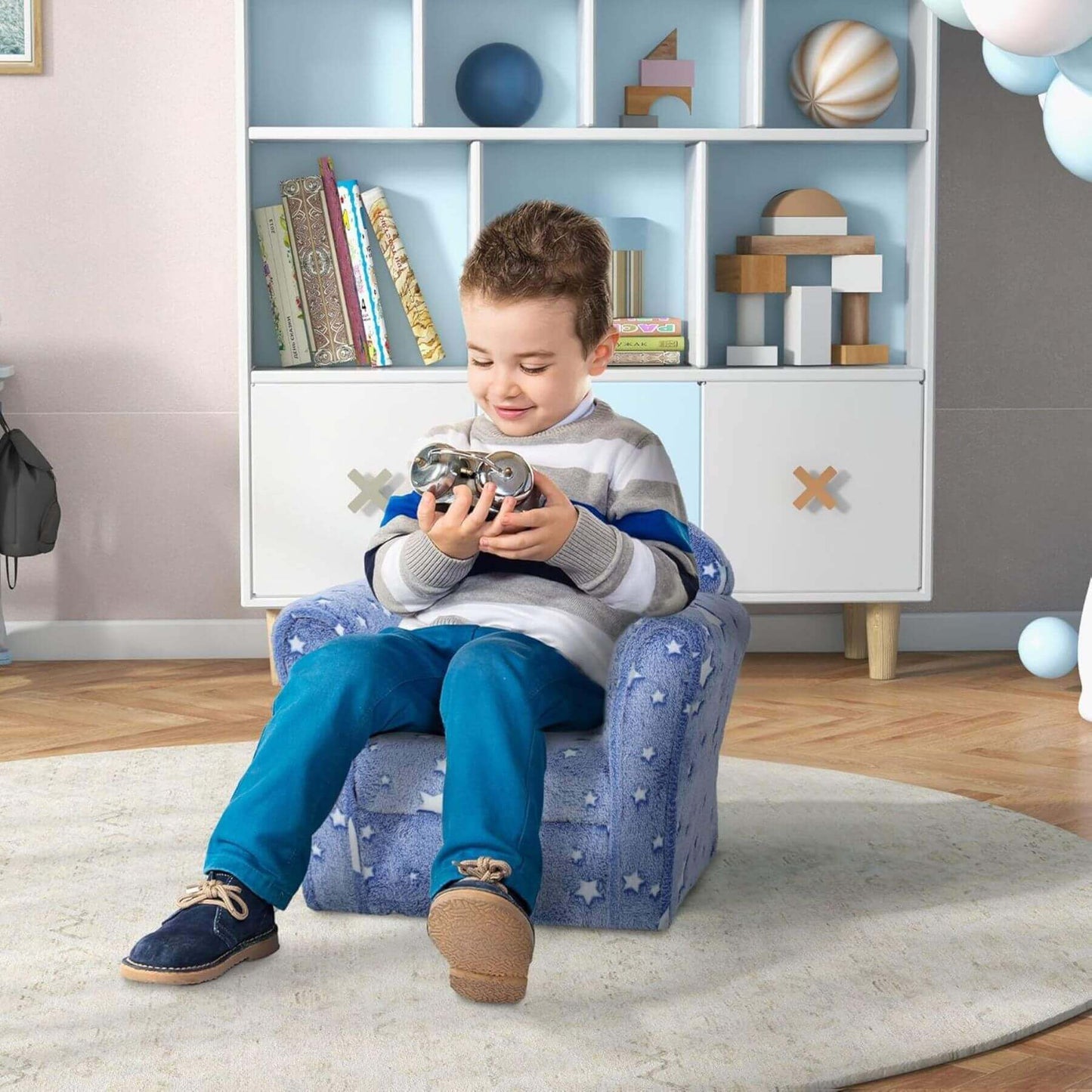 Child sitting on Qaba Kids Sofa with Glowing Star Design Blue playing with a toy in a room with shelves and toys.