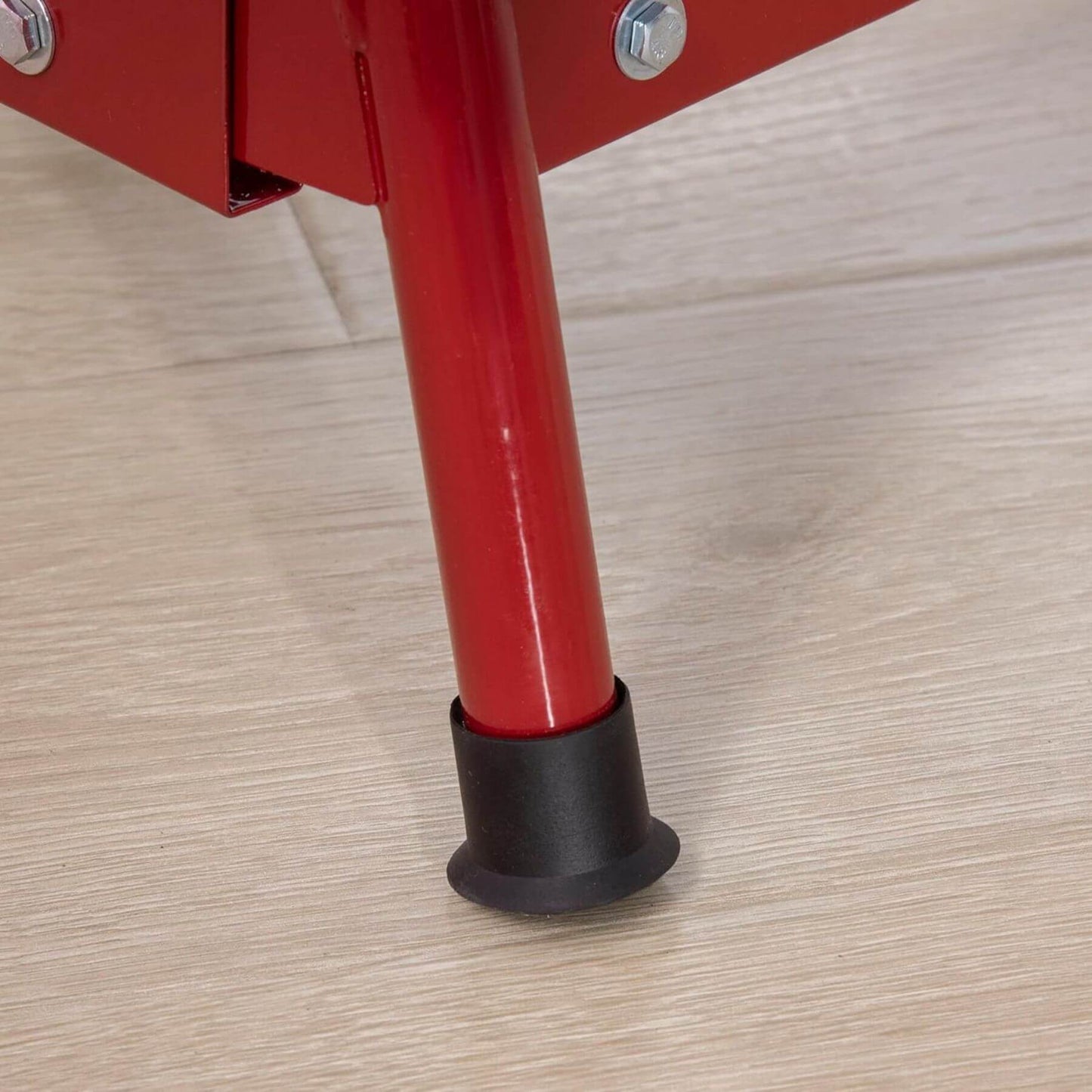 Red metal leg with black rubber cap on a wooden floor