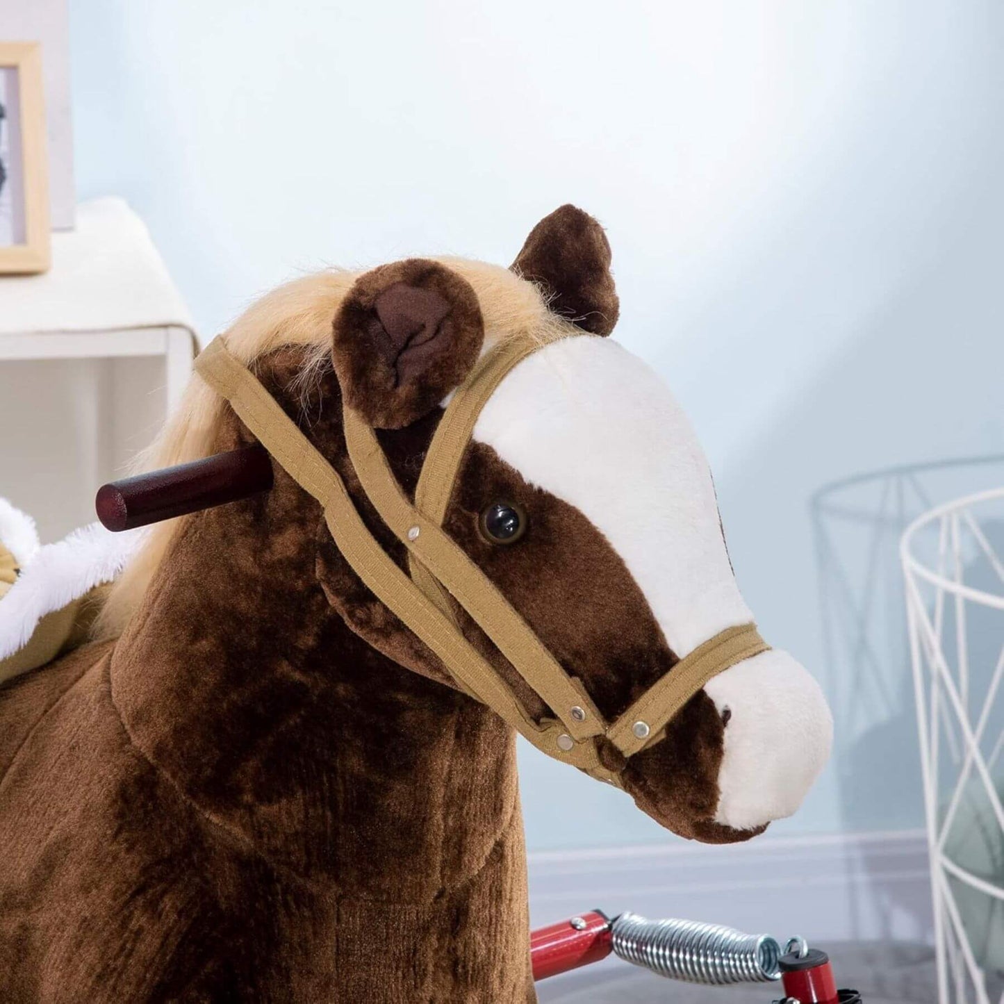 Close-up of a brown and white plush horse ride-on with a blurred background