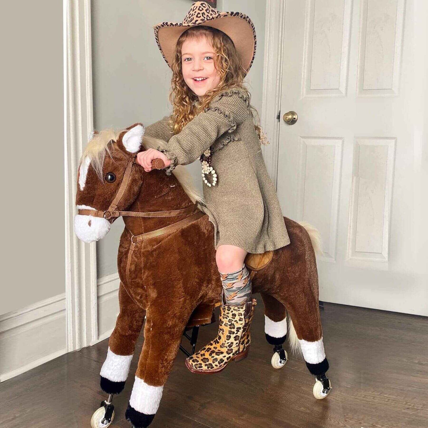 Child riding Qaba Kids Ride-on Walking Horse with Easy Rolling Wheels Brown in a room with a neutral color scheme.