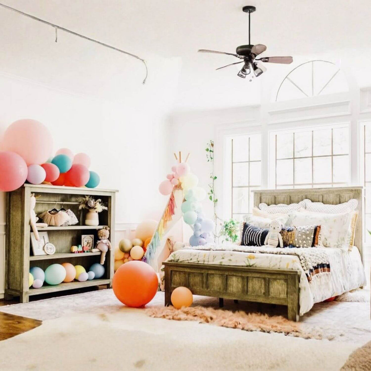 Children's bedroom with colorful balloons, a bed, and shelves.