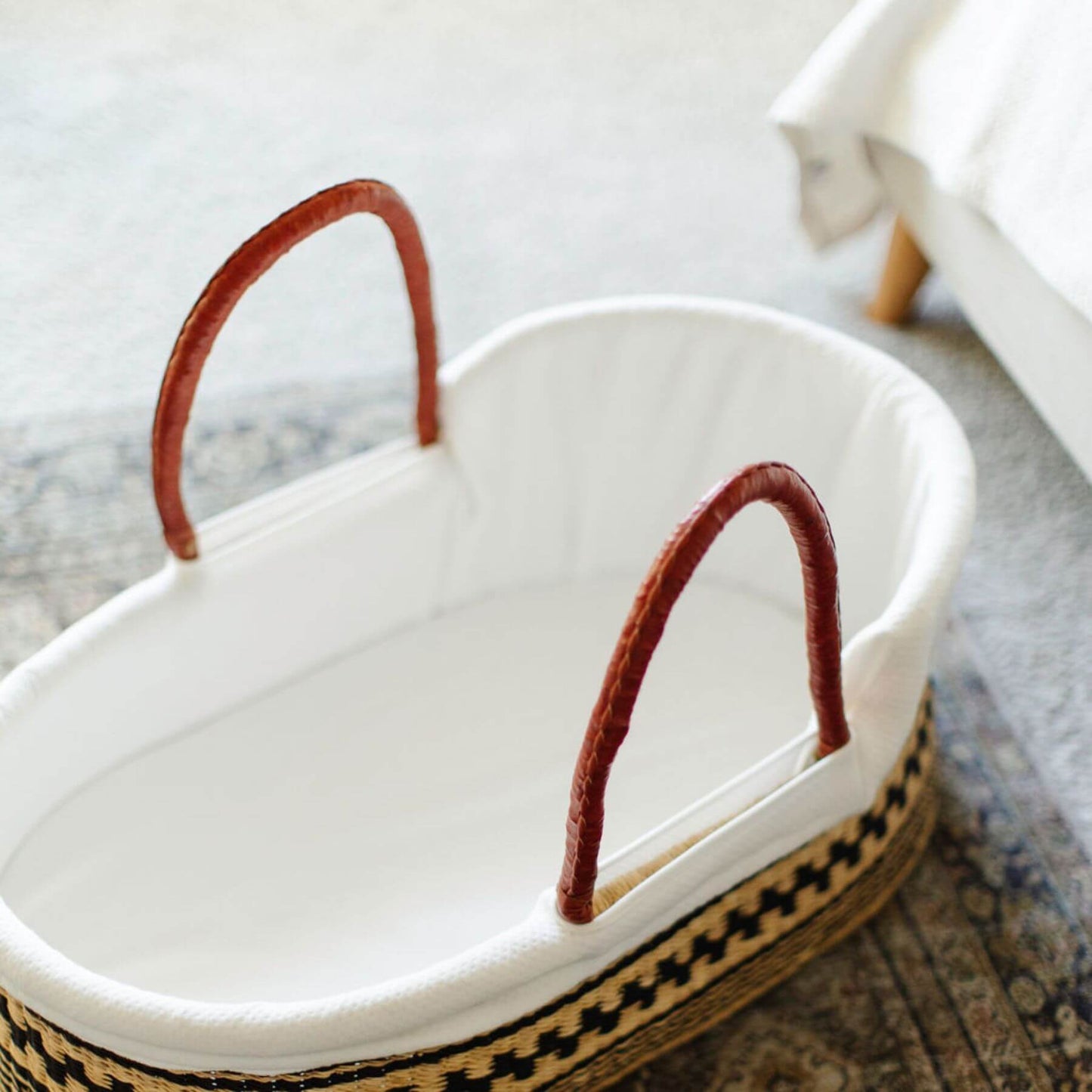 Plum+Sparrow Remy African Moses Basket on a textured surface