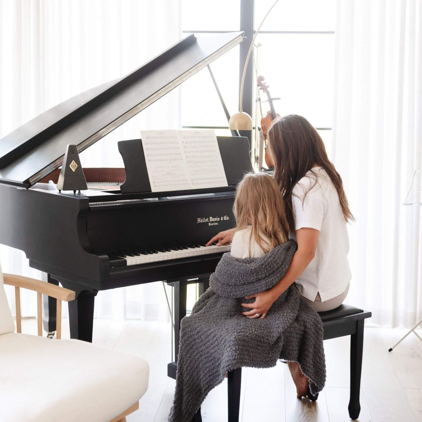 Woman and child playing a piano together in a bright room, wrapped in Ribbed Bamboni® Throw Blanket Charcoal