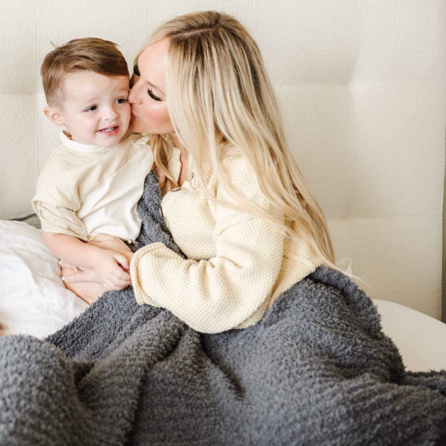 Woman kissing a child on the cheek while sitting together under Ribbed Bamboni® Throw Blanket Charcoal