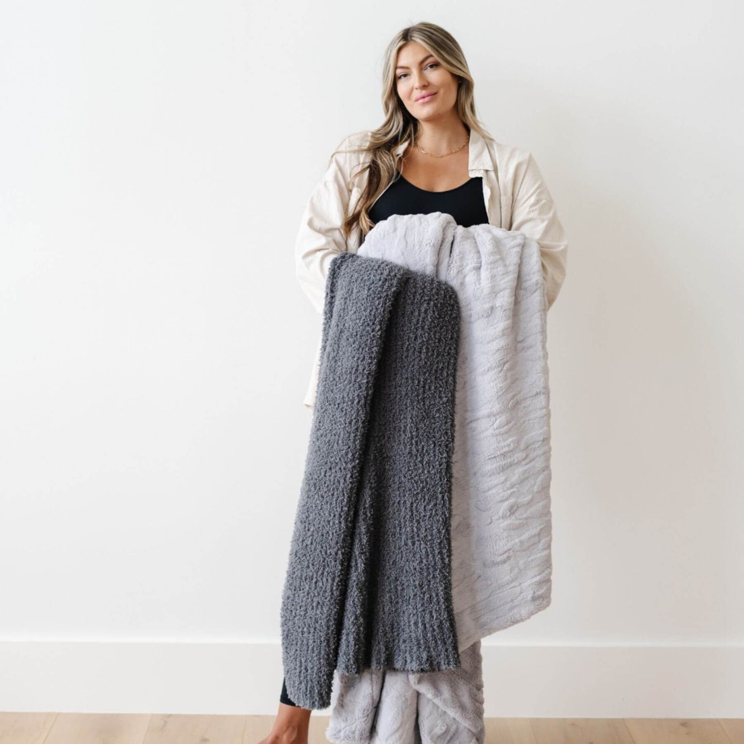 Woman holding Ribbed Bamboni® Throw Blanket Charcoal against a white background