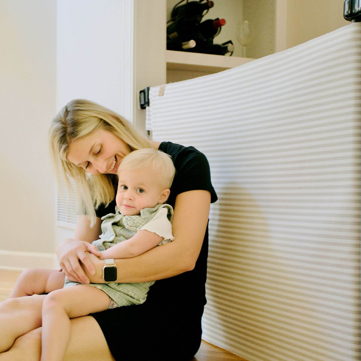 Woman holding a baby in front of a safety gate