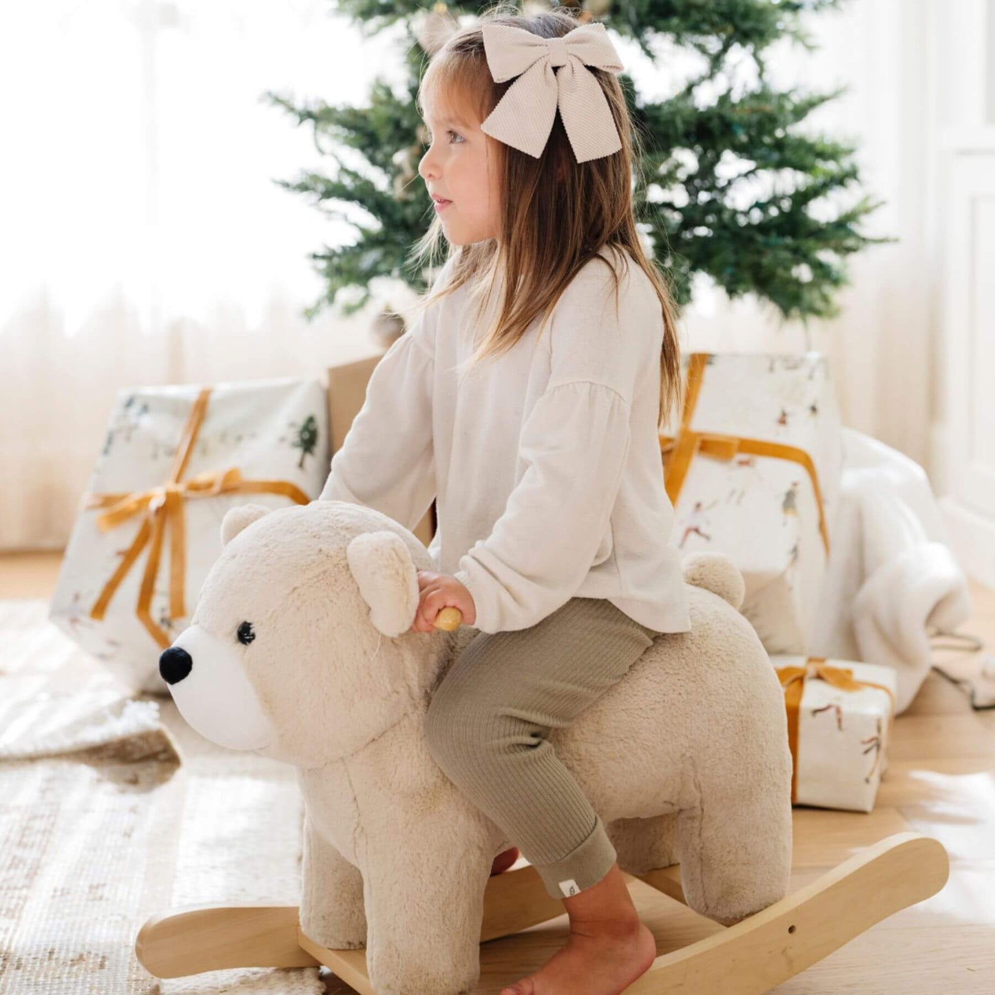 Child riding Saranoni Stuffed Animal Rocker - Bear in a festive setting with Christmas decorations.