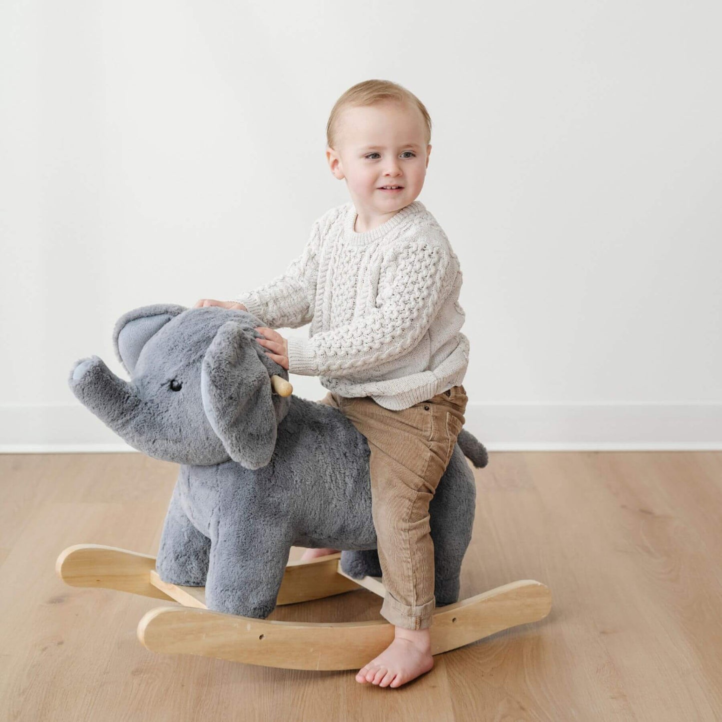 Child riding Saranoni Stuffed Animal Rocker - Elephant on a wooden floor.
