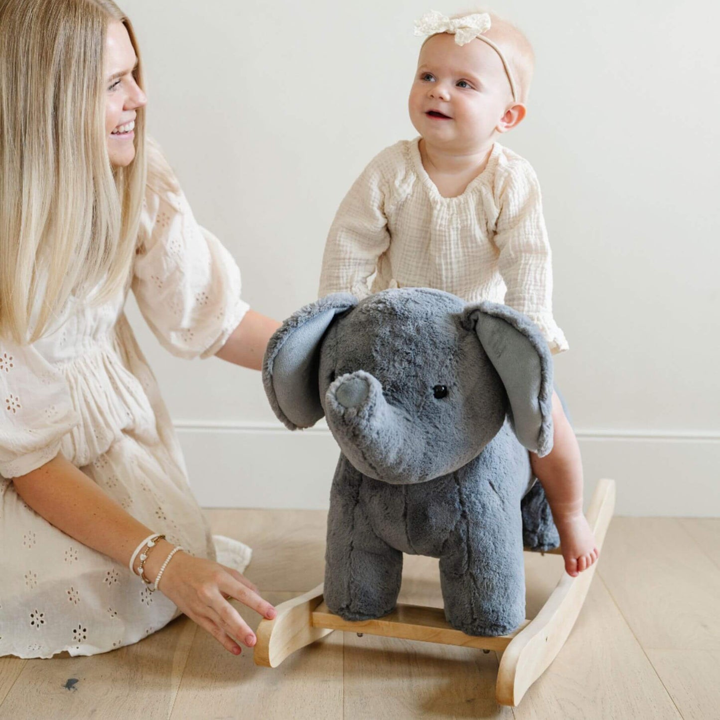 Woman and baby playing with Saranoni Stuffed Animal Rocker - Elephant on a wooden stand.