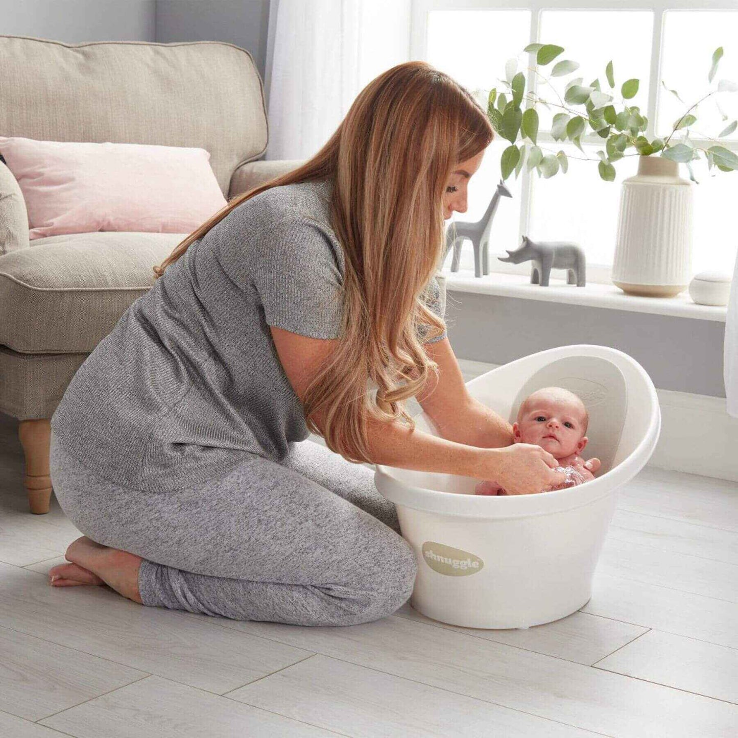 Woman bathing a baby in Shnuggle Bath in a bright, home setting.