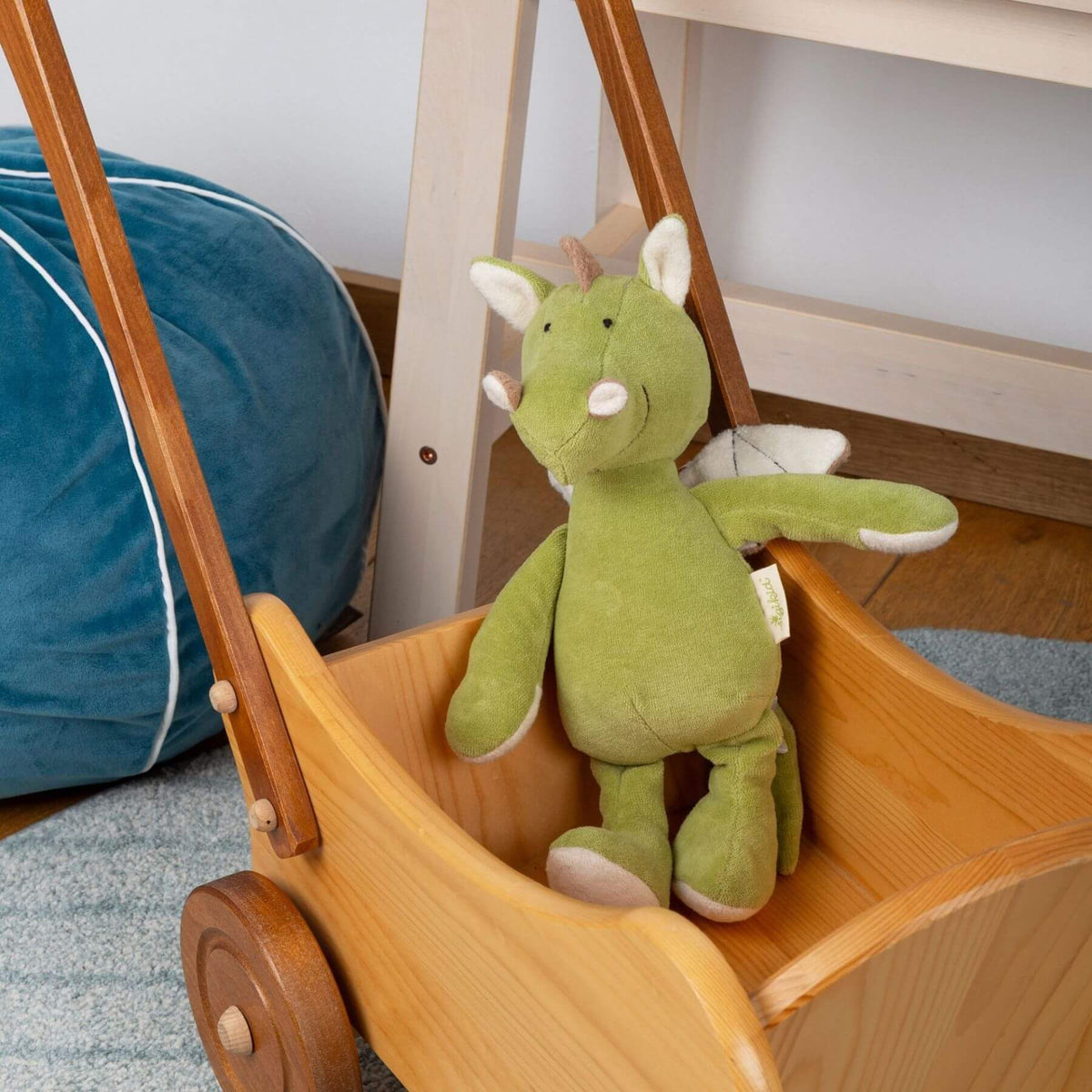 sigikid Organic Dragon Plush Toy in a wooden toy car with a blue bag in the background