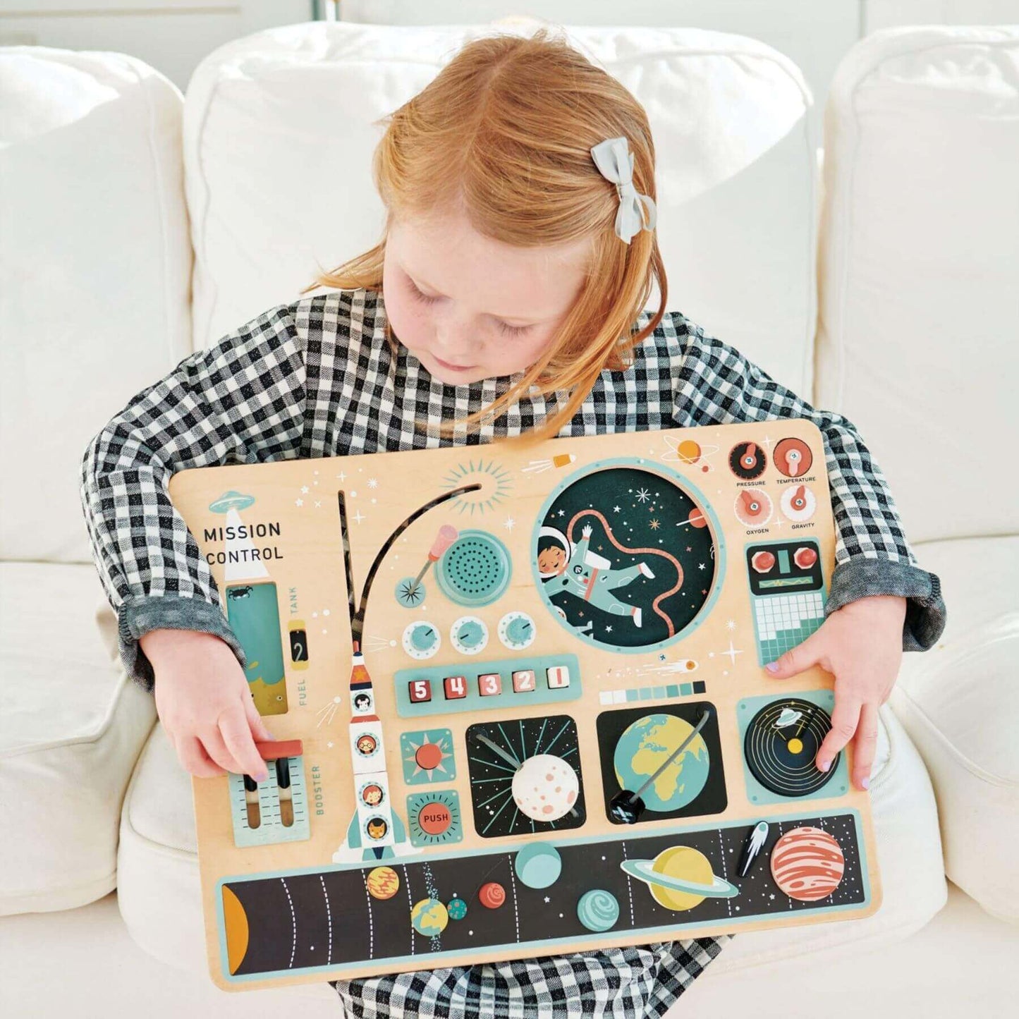 Child holding Tender Leaf Space Station on a white couch