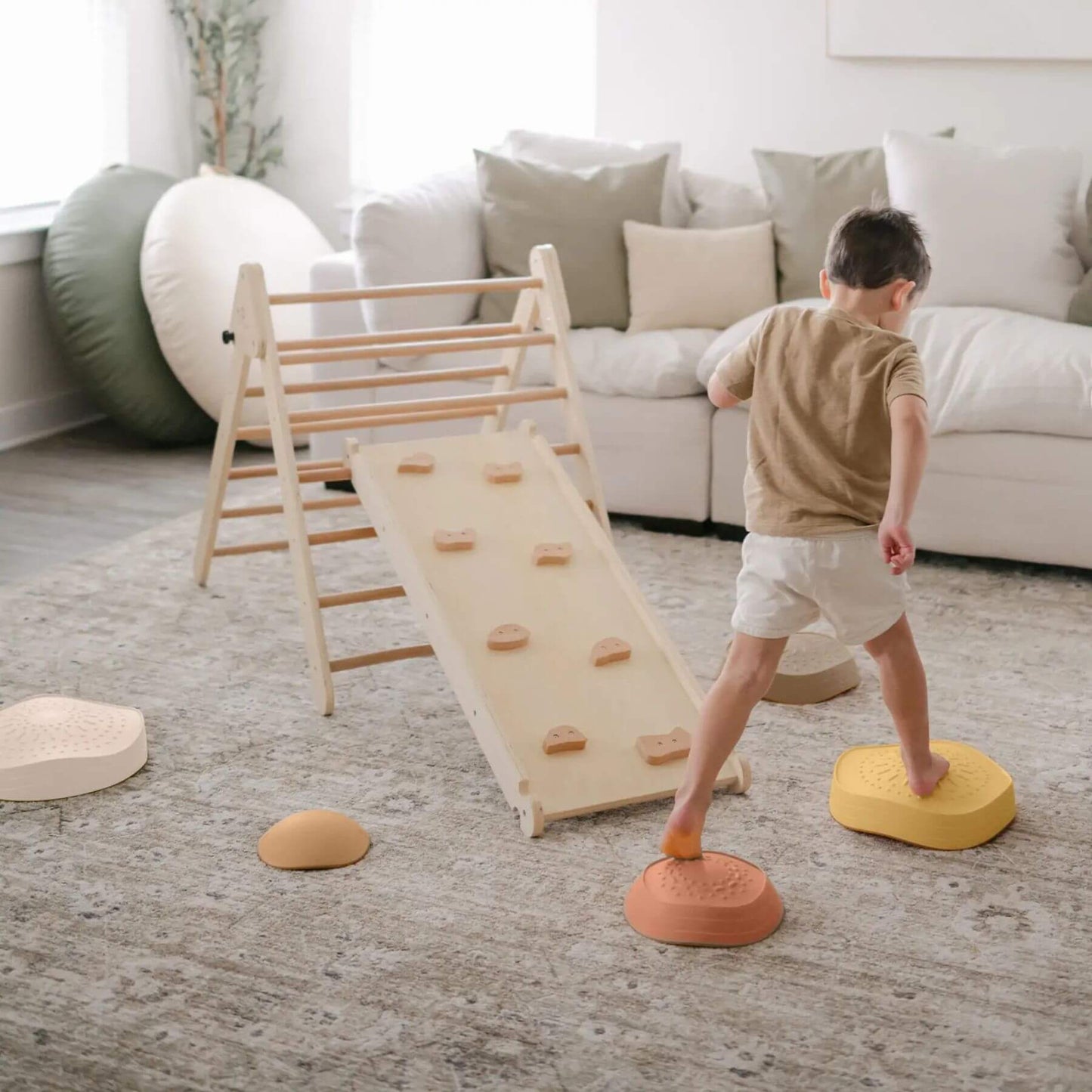 Child playing with Tiny Land® Stepping Stones - Sunset Hues in a living room setting