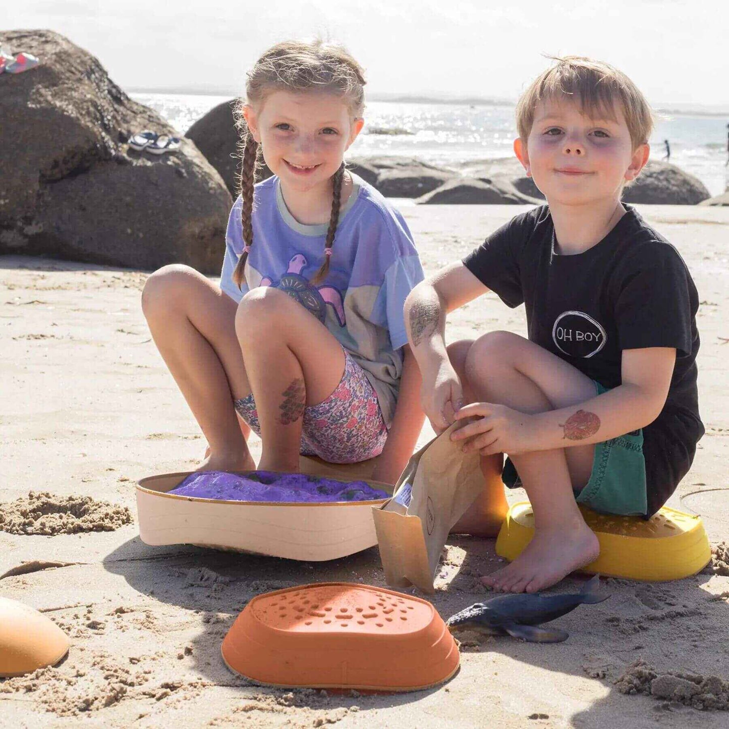 Two children sitting on Tiny Land® Stepping Stones - Sunset Hues with a scenic background