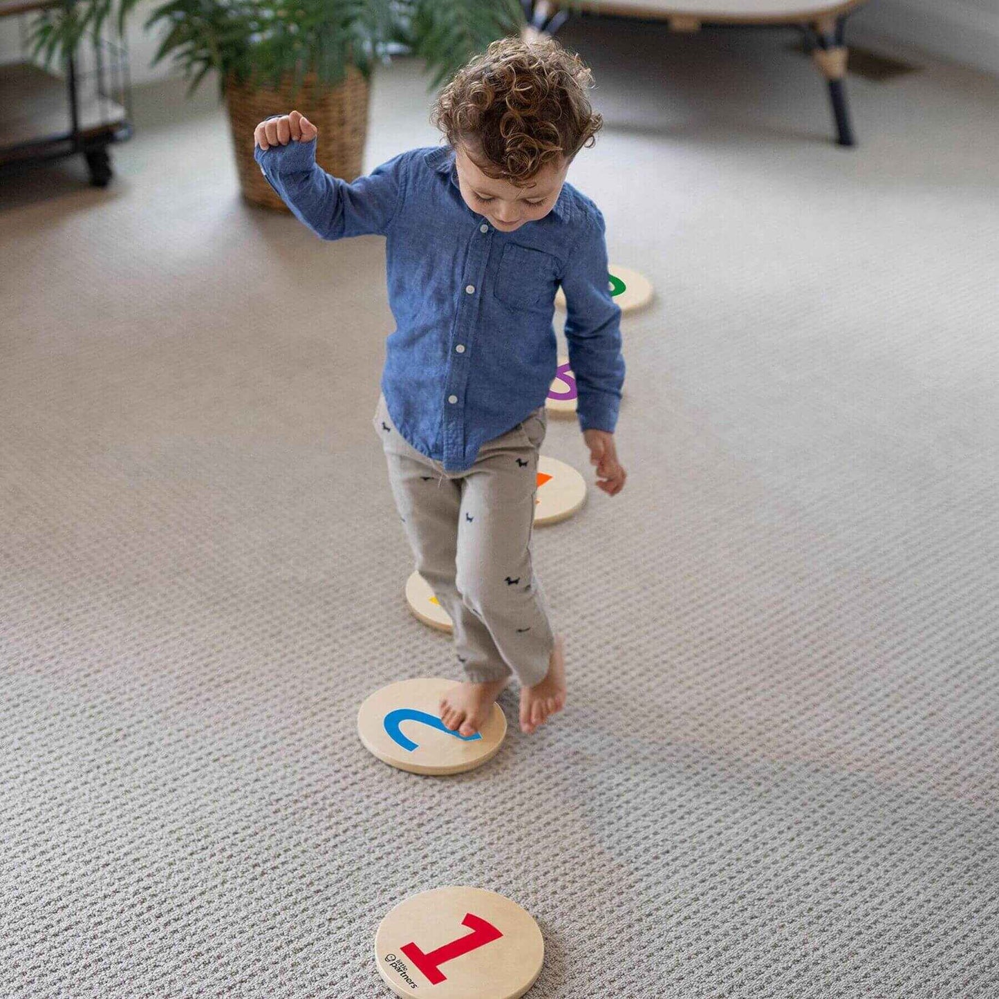 Child playing with Little Partners Step 'N Learn Stepping Stones on a carpeted floor