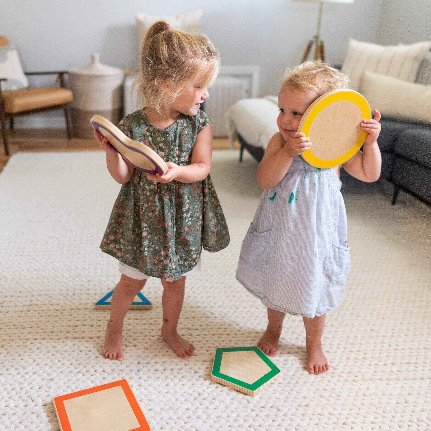 Two young children playing with Little Partners Step 'N Learn Stepping Stones Shapes on a carpeted floor.