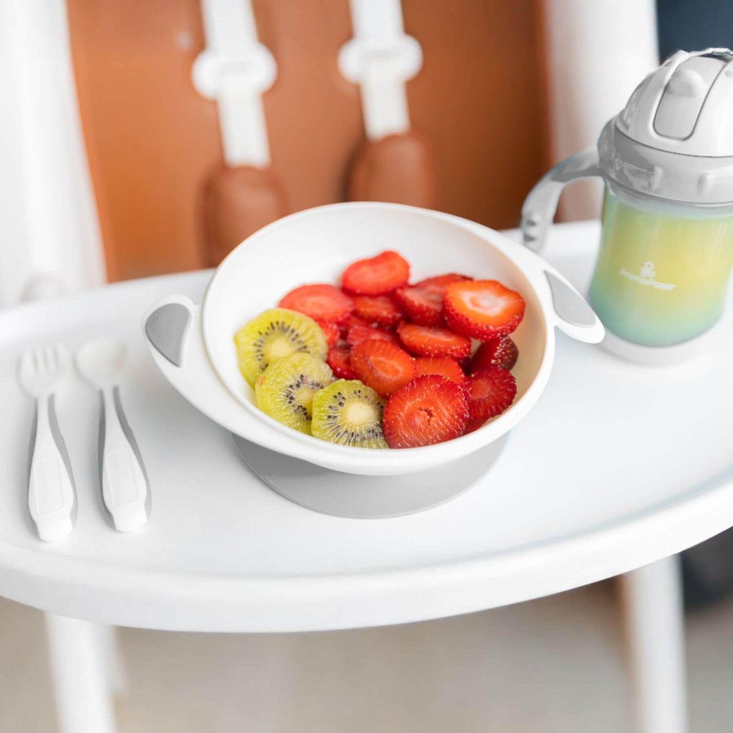 Fruit bowl with strawberries and kiwis on a high chair tray