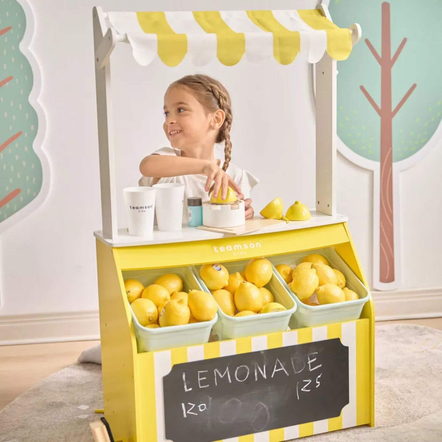 Child playing with Teamson Sunny Citrus Lemonade Stand Playset in a room.