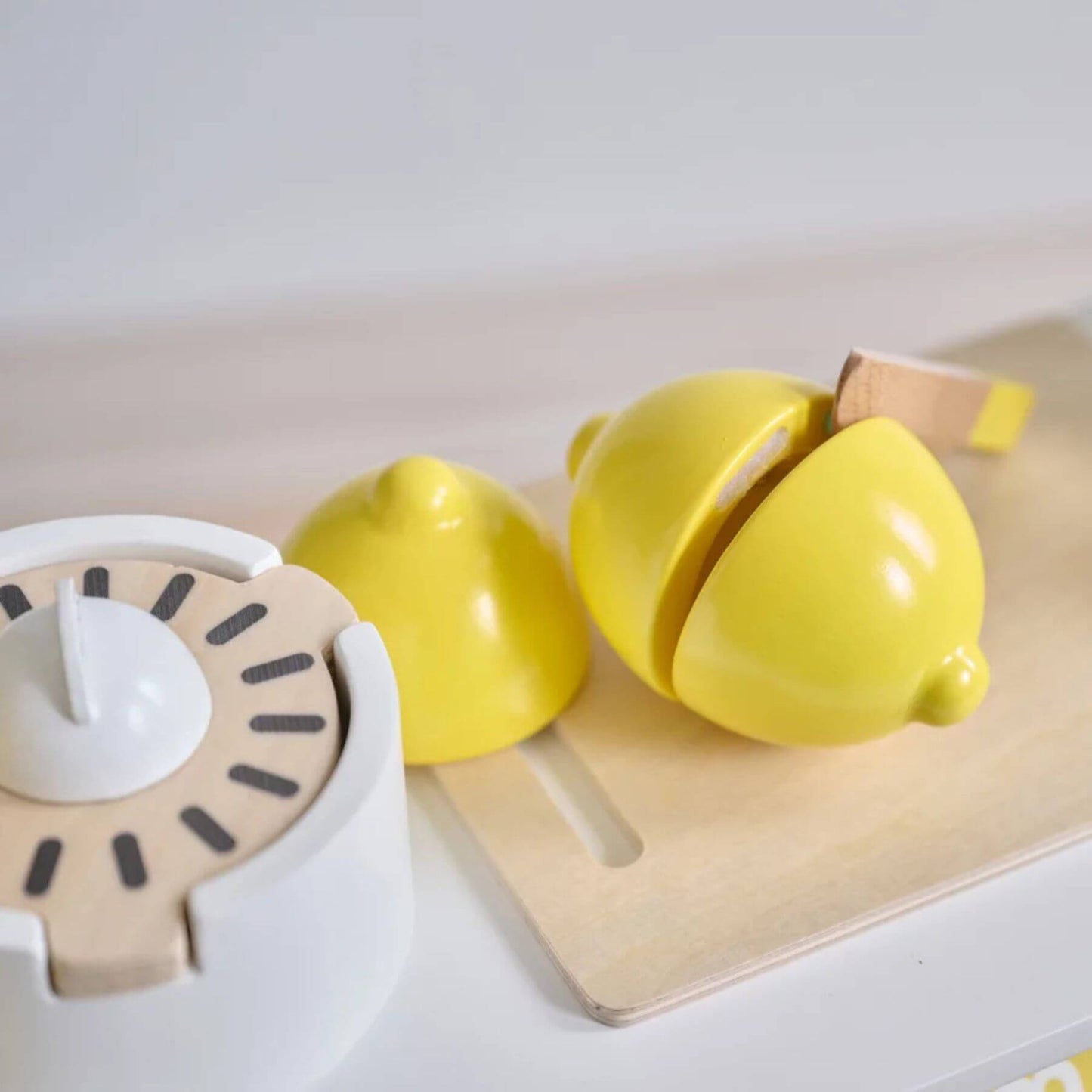 Yellow kitchen timer and lemon-shaped container on a white surface