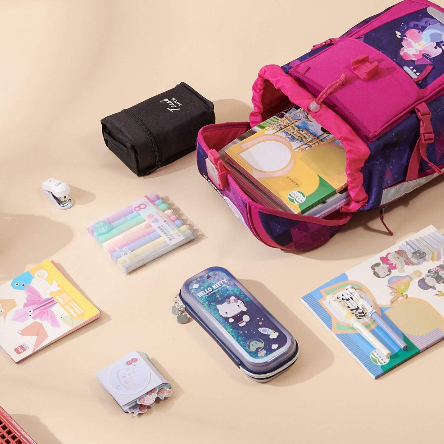Open Sunveno Over-clip Kids School Backpack Pink with stationery items on a beige background