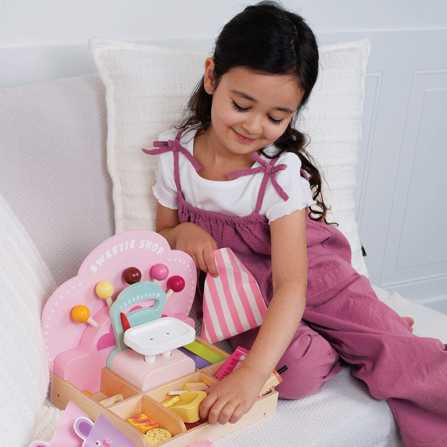 Young girl playing with Tender Leaf Sweetie Pic'n'Mix Shop on a white couch.