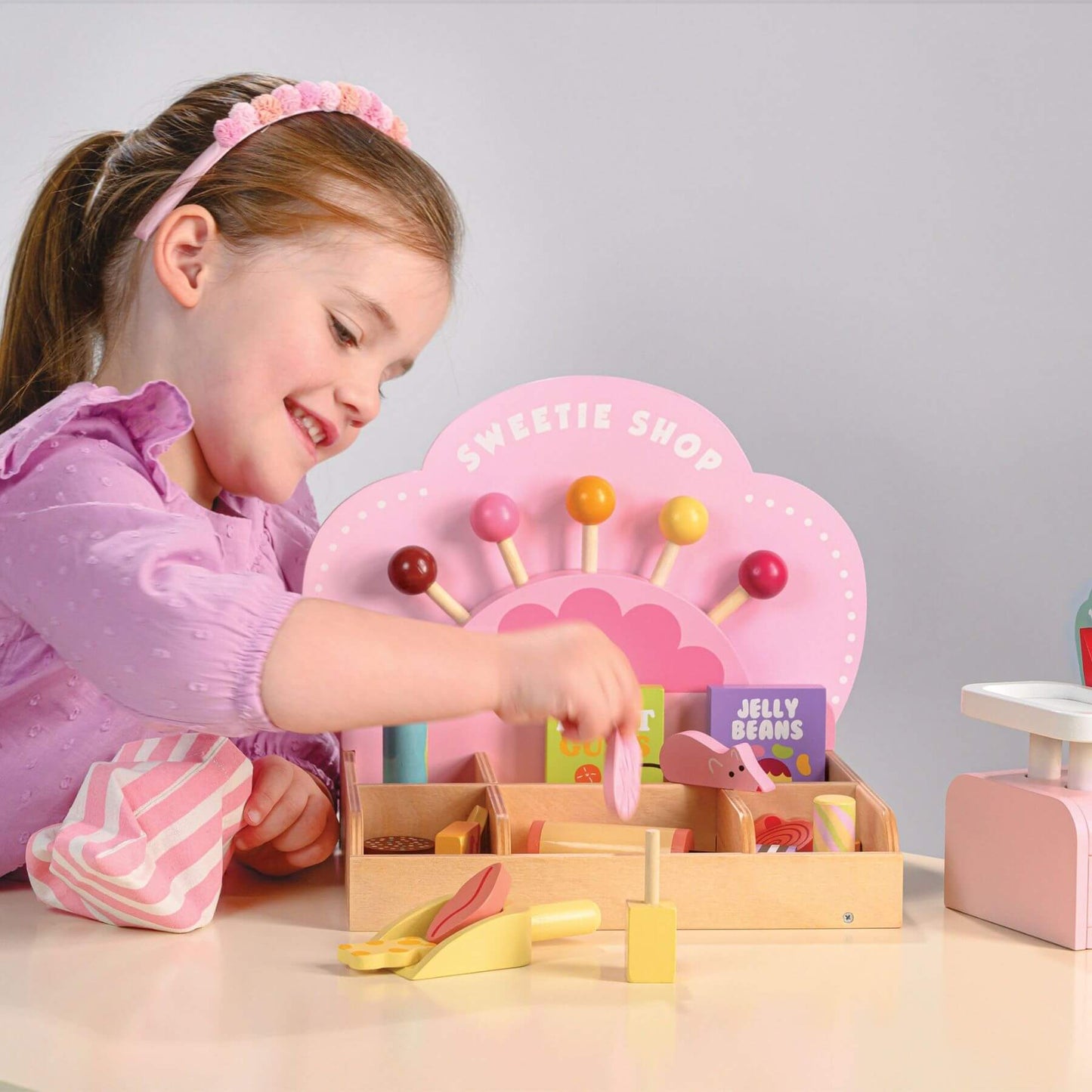 Child playing with Tender Leaf Sweetie Pic'n'Mix Shop on a light surface.