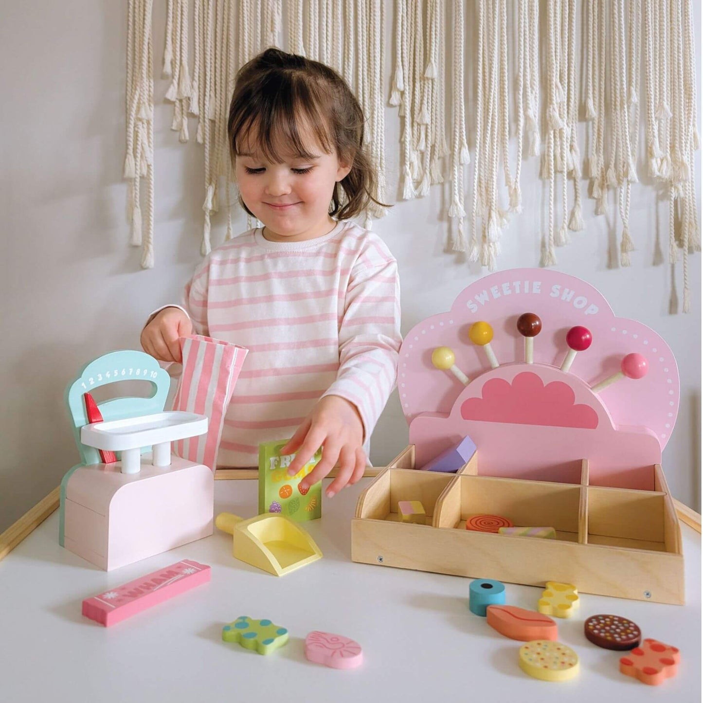 Child playing with Tender Leaf Sweetie Pic'n'Mix Shop on a white surface.