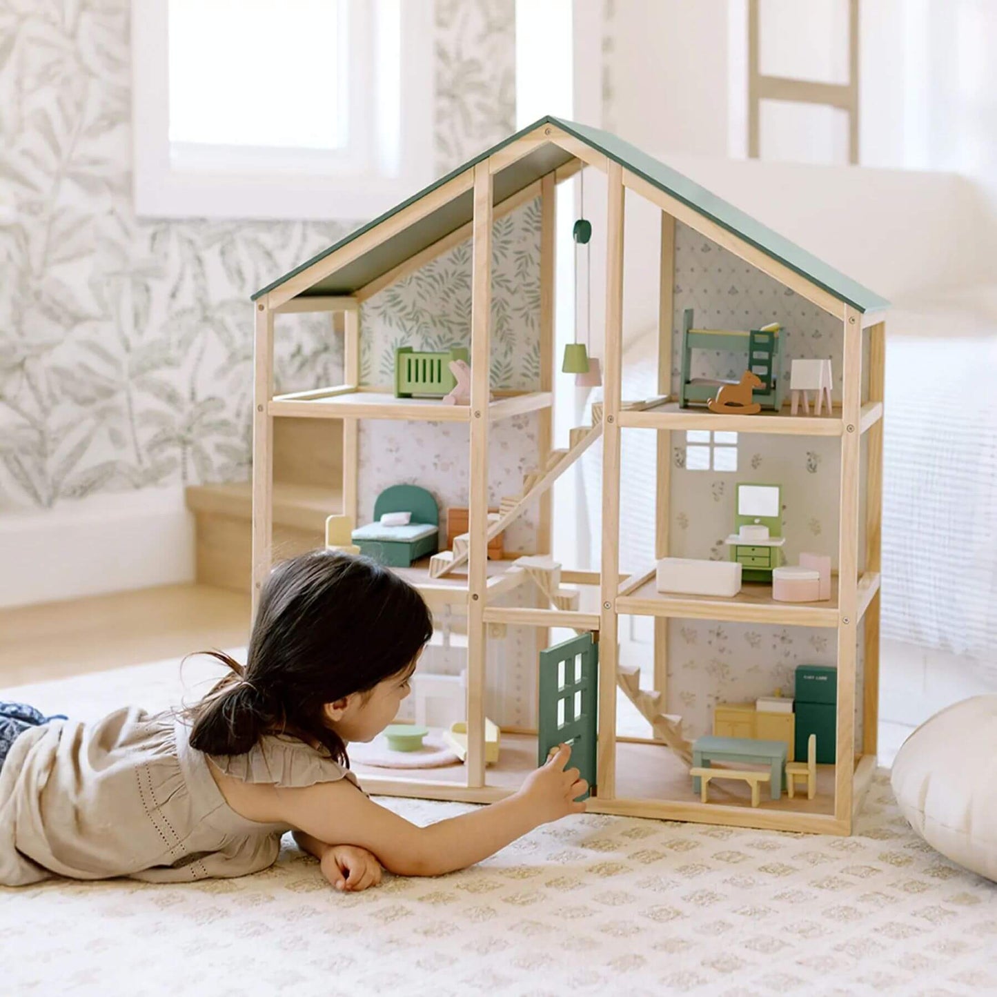 Child playing with Sweetwood Evergreen Dollhouse in a bright room.