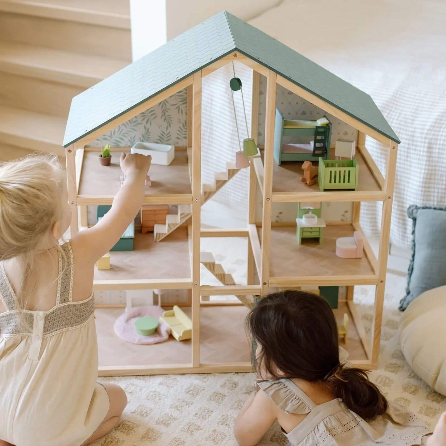 Two children playing with Sweetwood Evergreen Dollhouse in a cozy room.