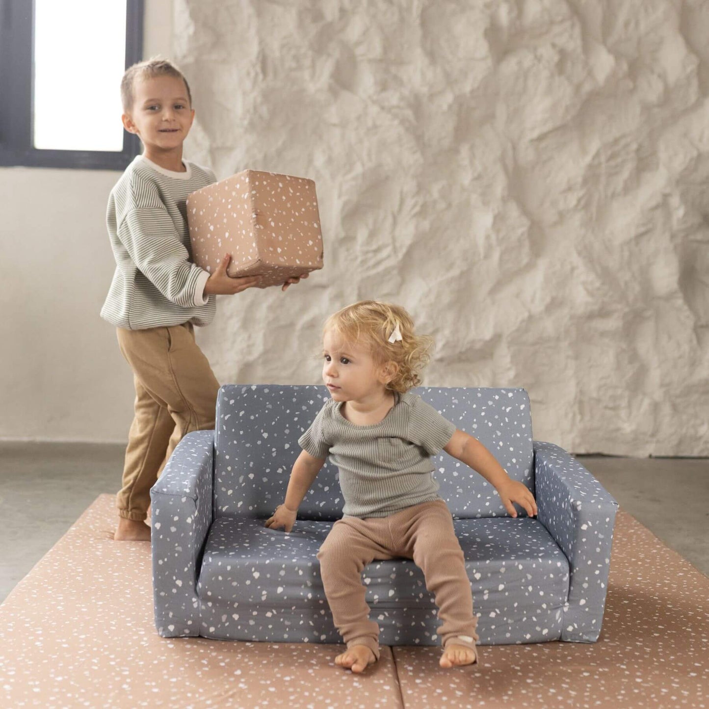 Boy holding Toki Kids Terrazzo Clay Play Cube with girl sitting on play sofa