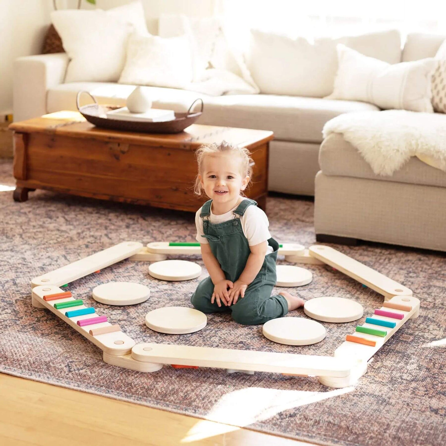 Child playing with Tiny Land® Balance Beam on a carpeted floor in a living room.
