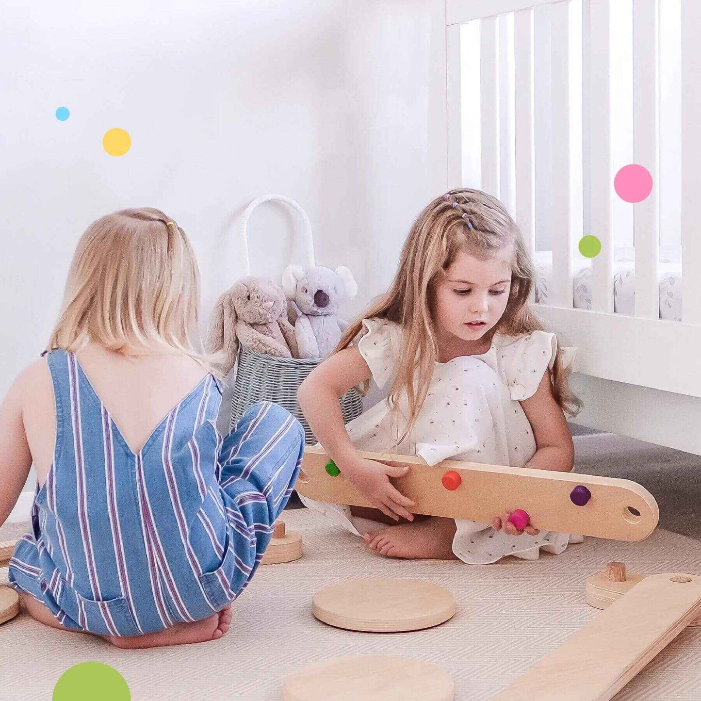 Two young girls playing with Tiny Land® Balance Beam on a light-colored floor.