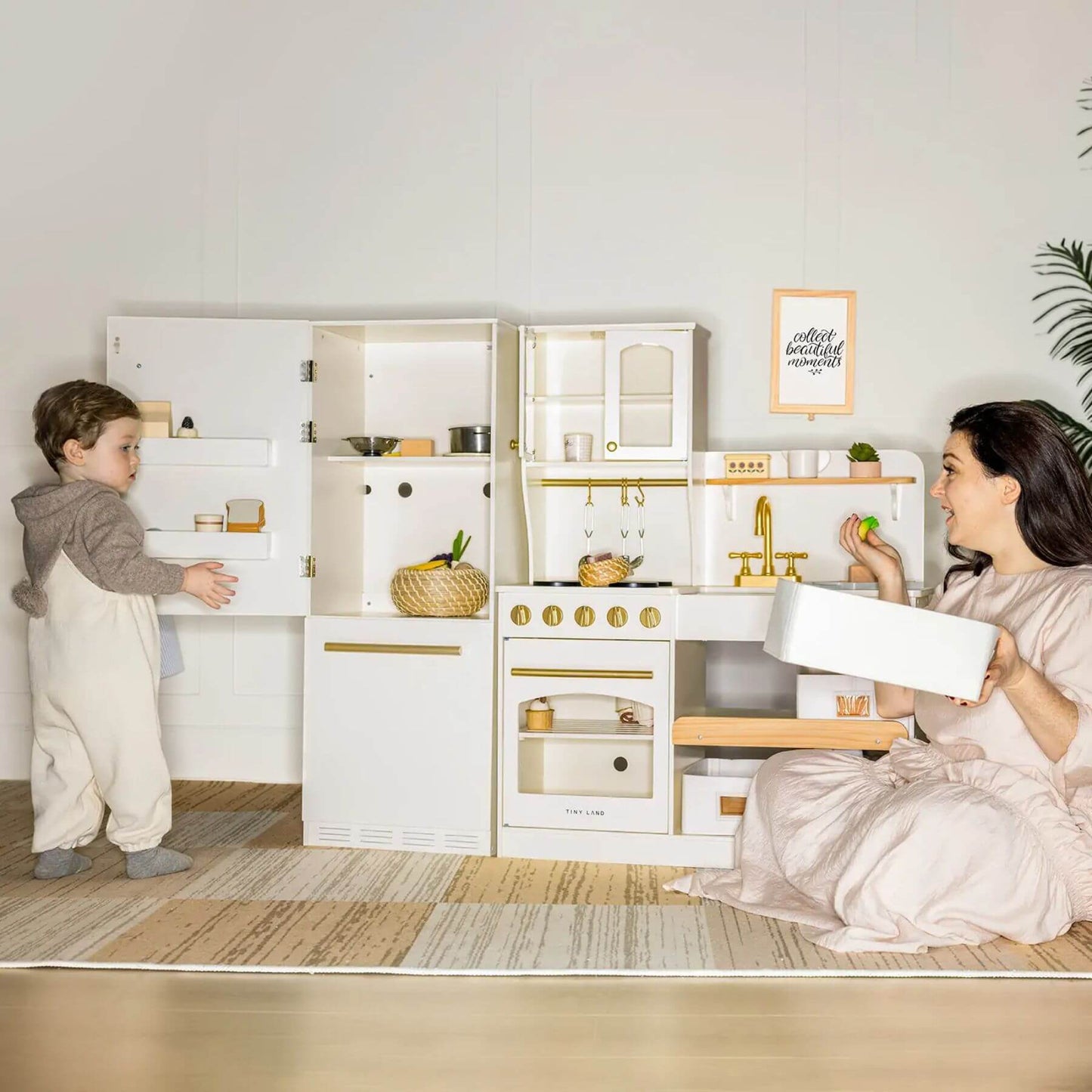 Two children playing with a toy kitchen set in a room.
