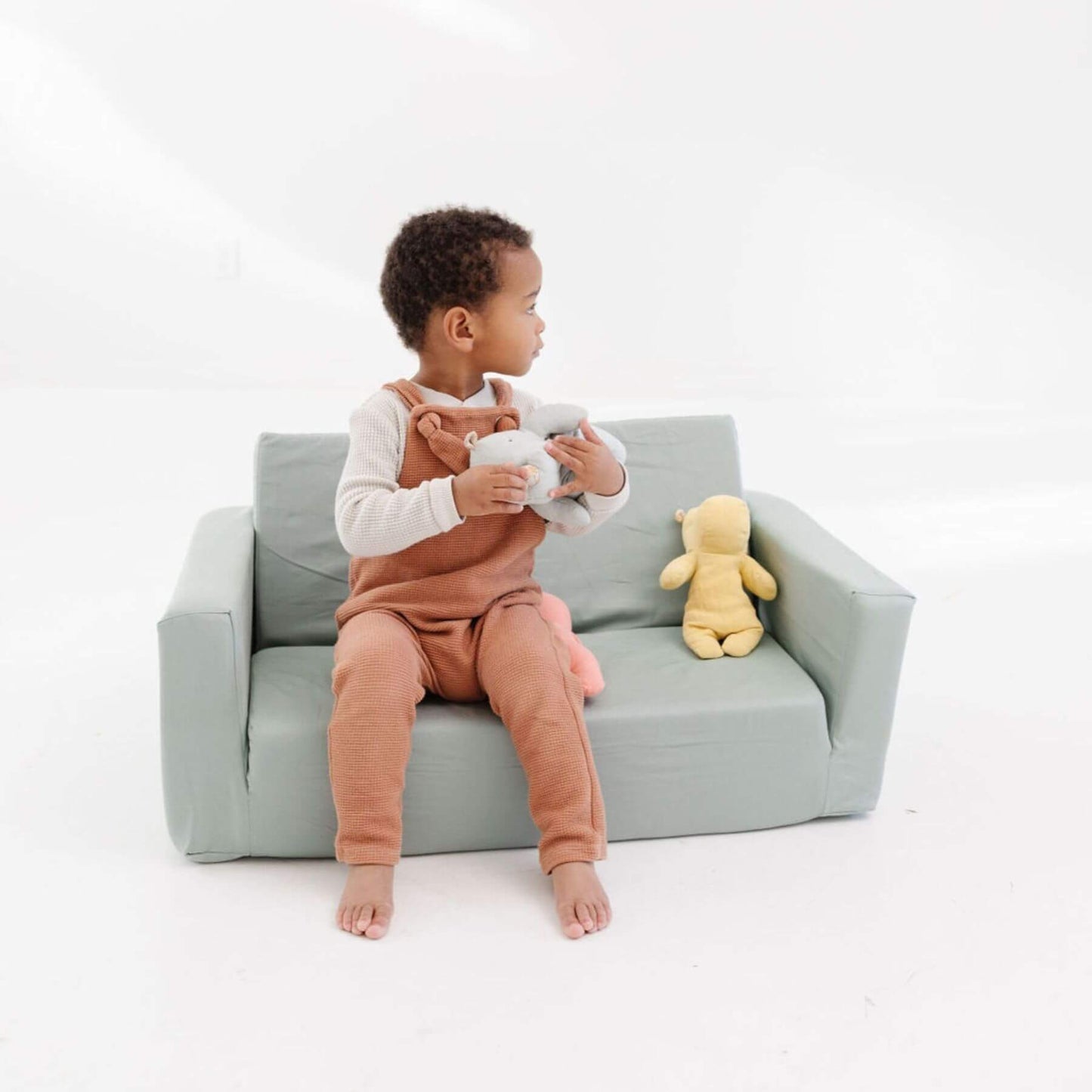 Child sitting on Toki Kids Sage Play Couch holding teddy bears